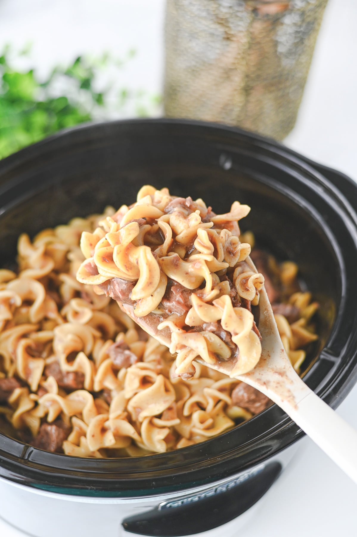 Finished dish of crockpot beef and noodles scooped up on a spoon ready to serve for a family dinner.