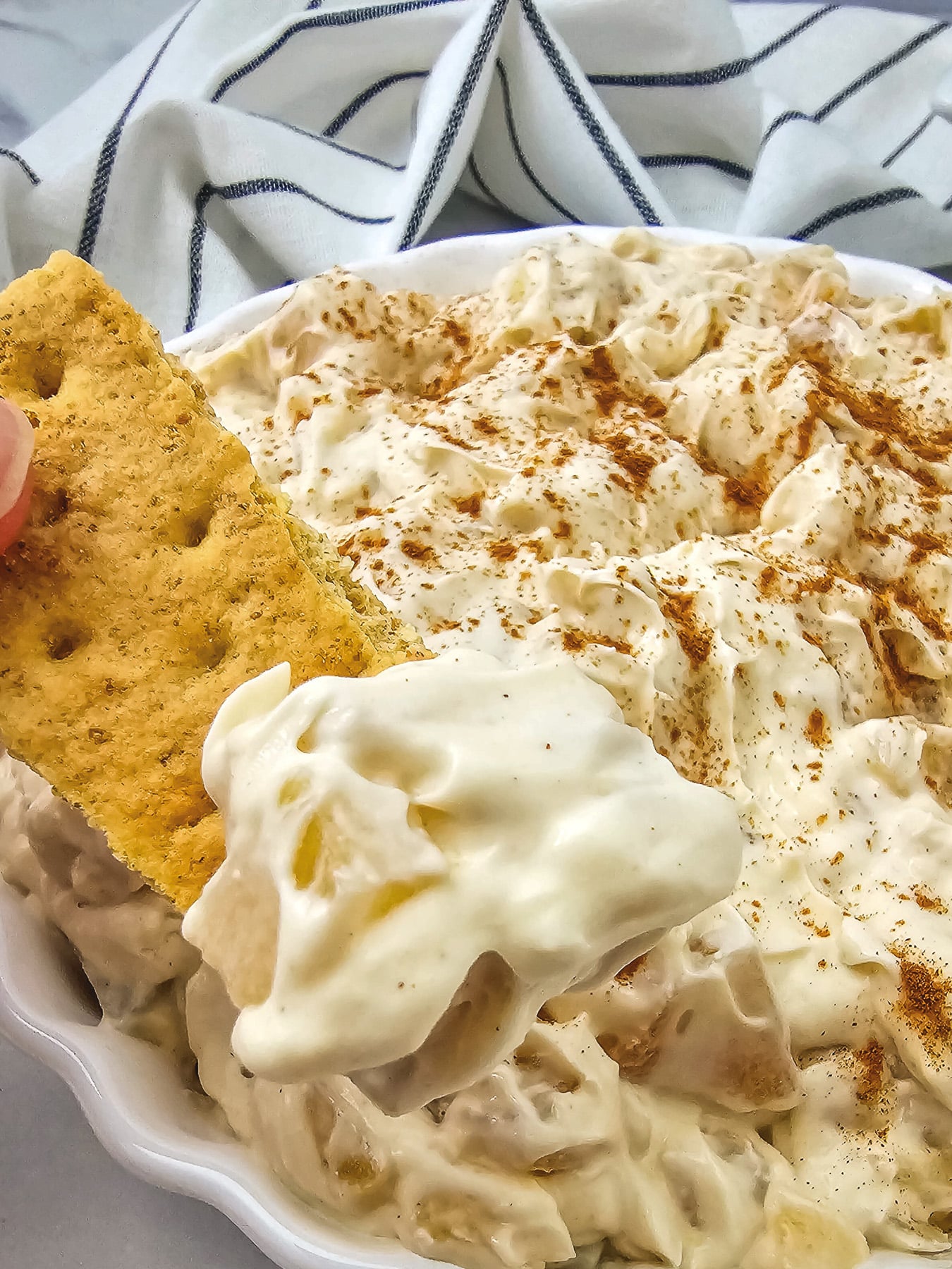 Apple dip in a bowl is dipped into with a Graham cracker.
