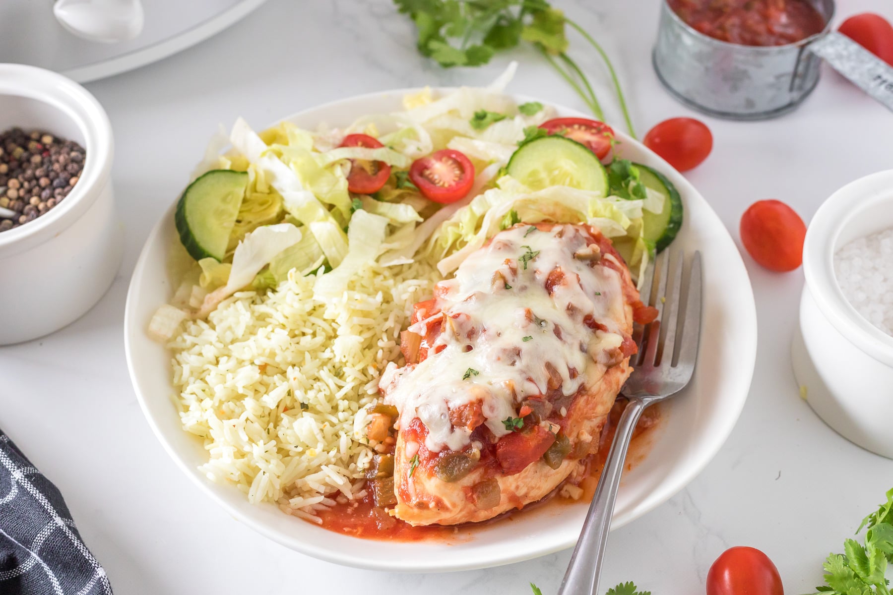Crockpot salsa chicken on a white plate with rice and a salad.