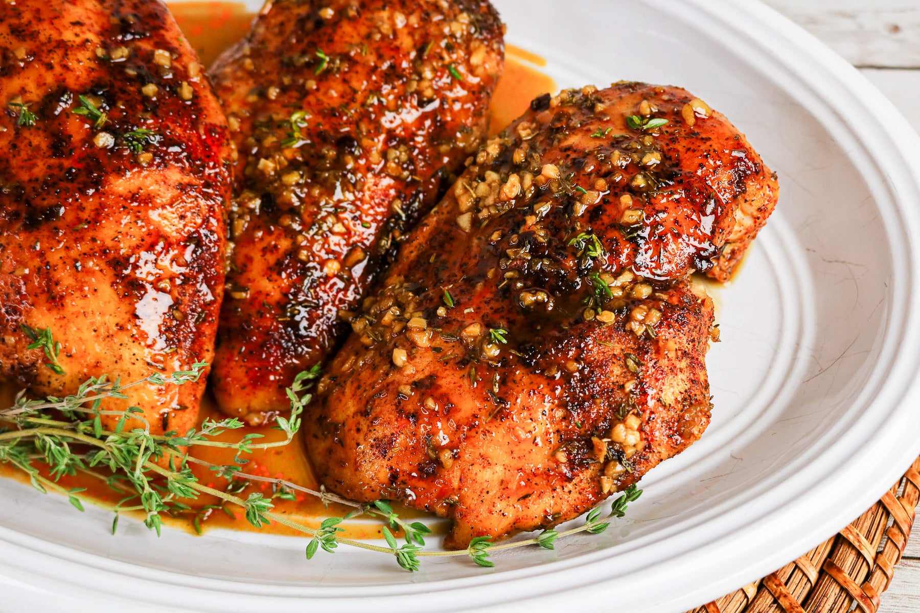 Side view of maple glazed chicken on a white plate.