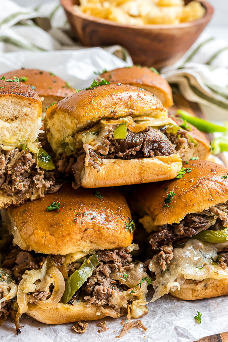 Philly cheesesteak sliders stacked on a plate.