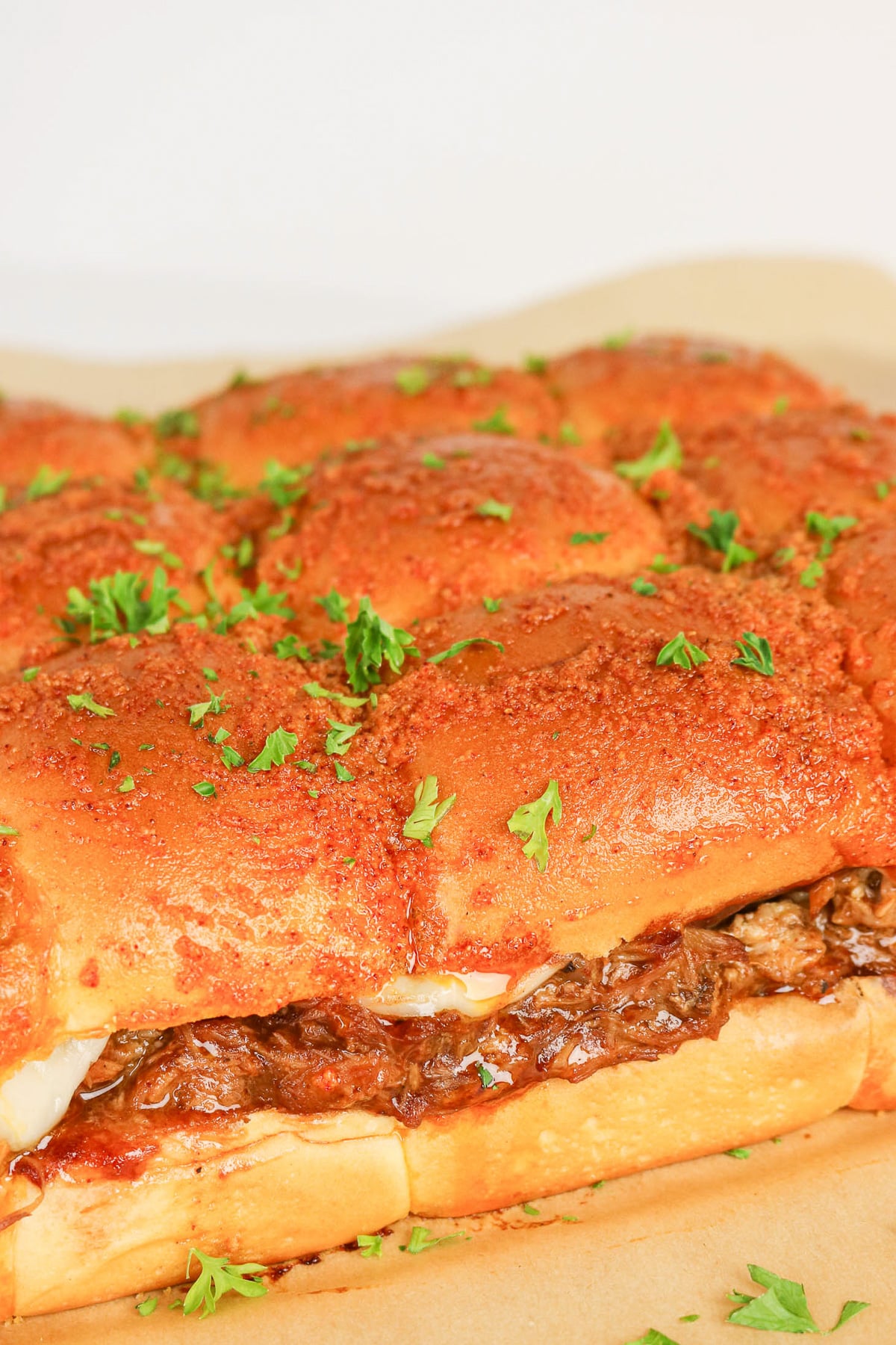 Pulled pork sliders on wooden serving board.