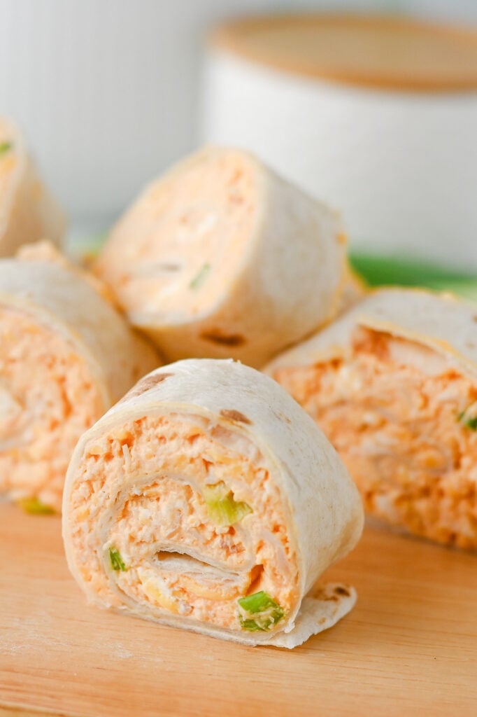 Buffalo chicken pinwheels on wooden serving board.