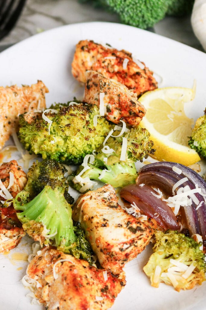Sheet pan chicken and broccoli served on a white plate.
