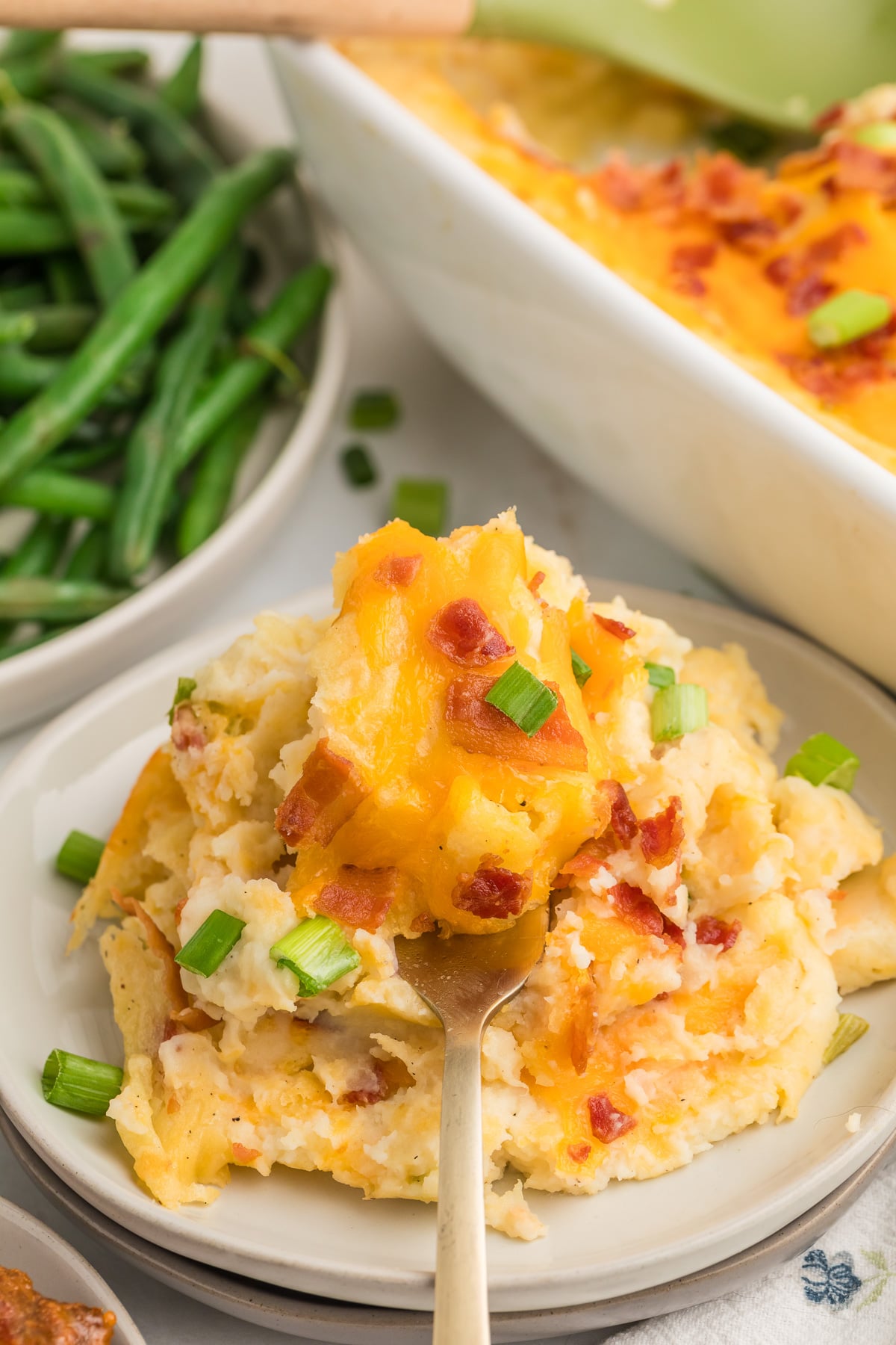 Twice Baked Mashed Potato Casserole served on a white plate.