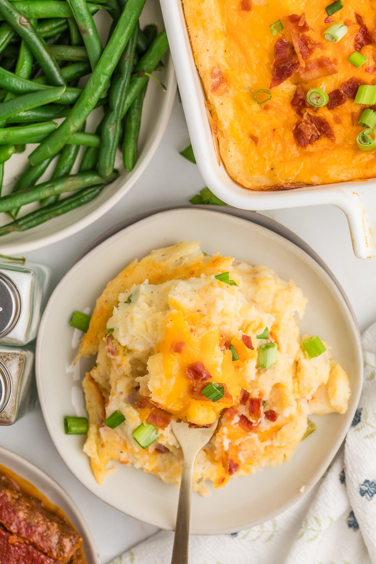 Twice baked mashed potato casserole on a white plate.