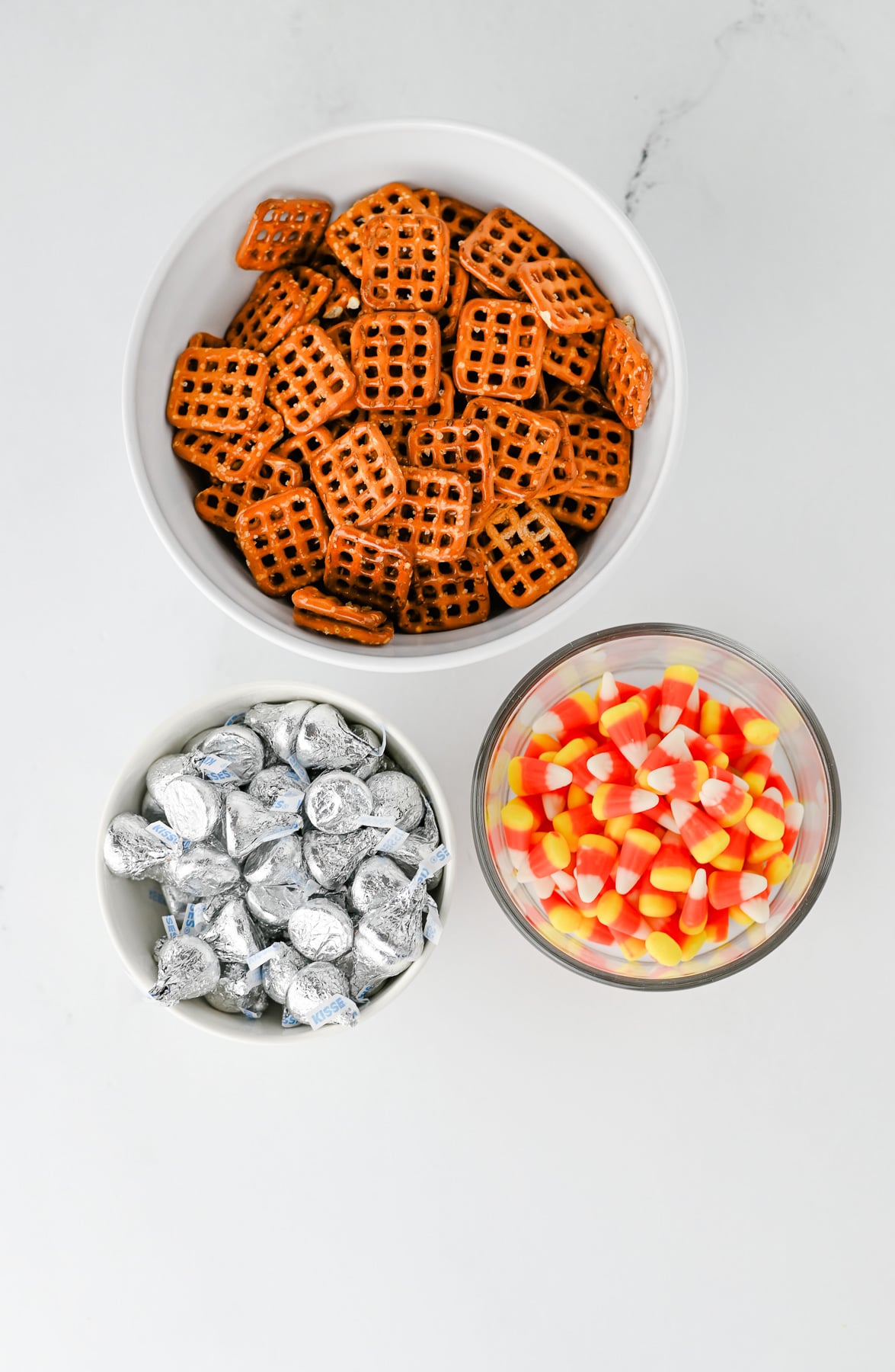 Ingredients for candy corn pretzel bites in small bowls on counter.