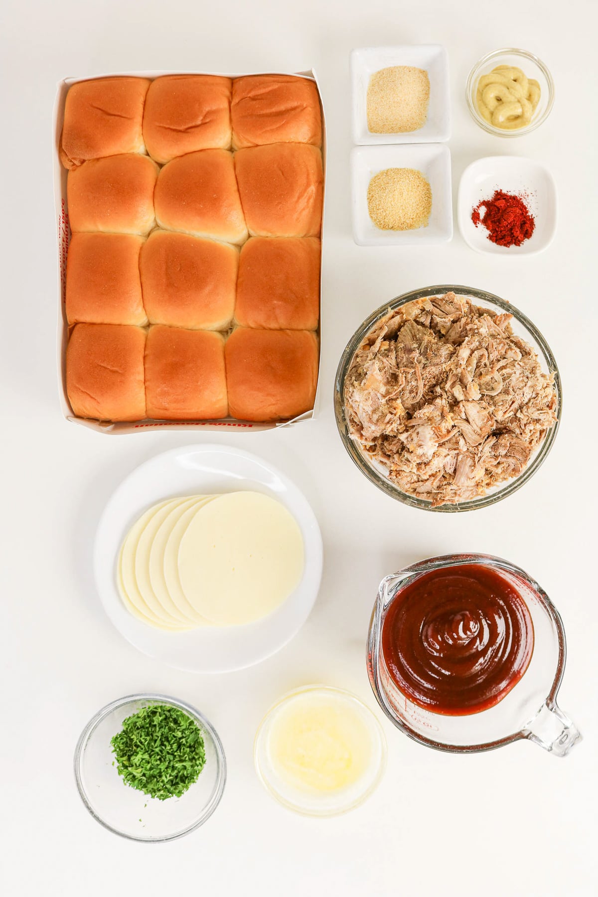Ingredients for pulled pork sliders in small bowls on kitchen counter in preparation for the recipe.