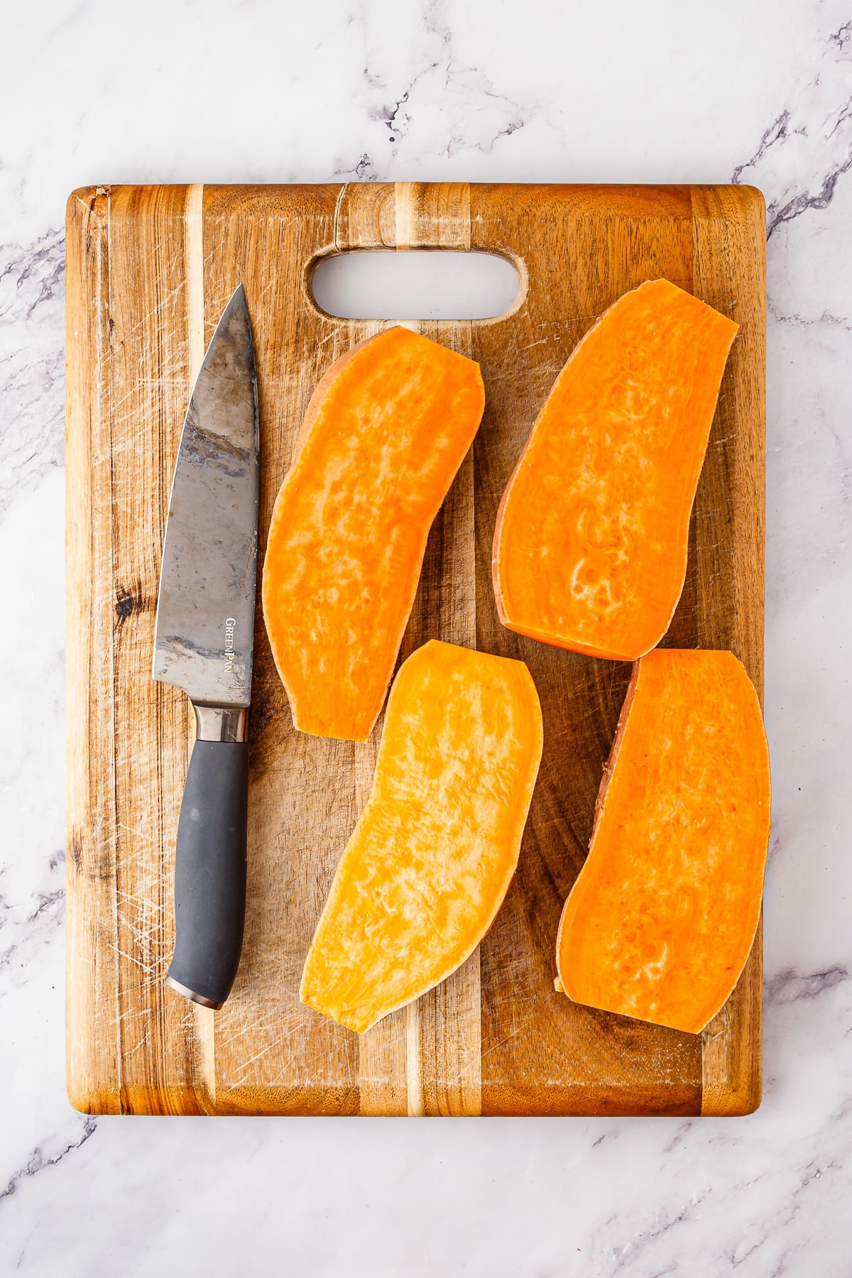 Cut sweet potatoes on wooden cutting board.