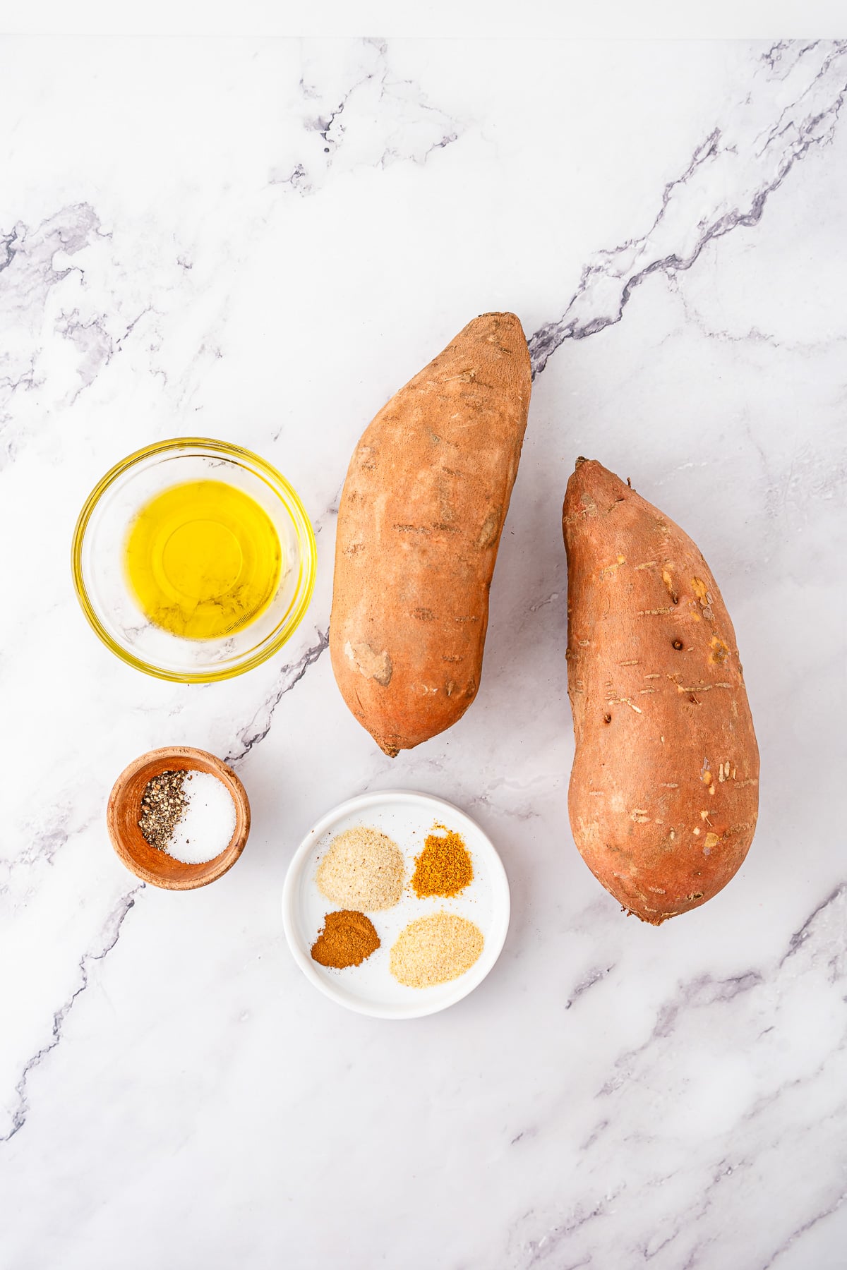 Ingredients for air fryer sweet potato fries laid out in small bowls on counter in preparation for the recipe.