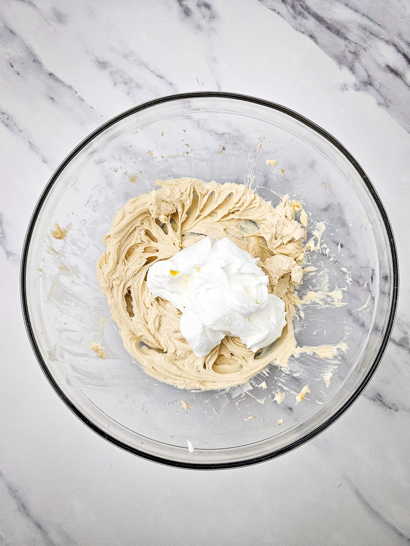 Whipped topping is added to the brown sugar and cream cheese mixture in glass bowl.