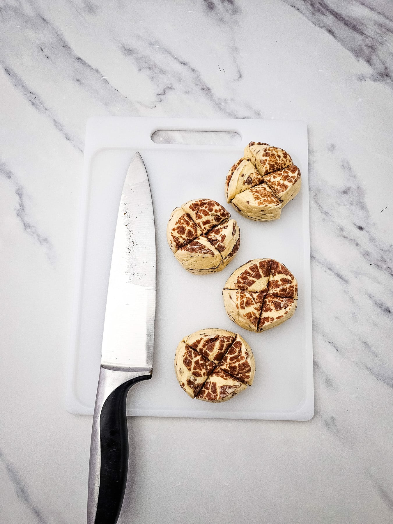 Unbaked cinnamon rolls on cutting board with knife.