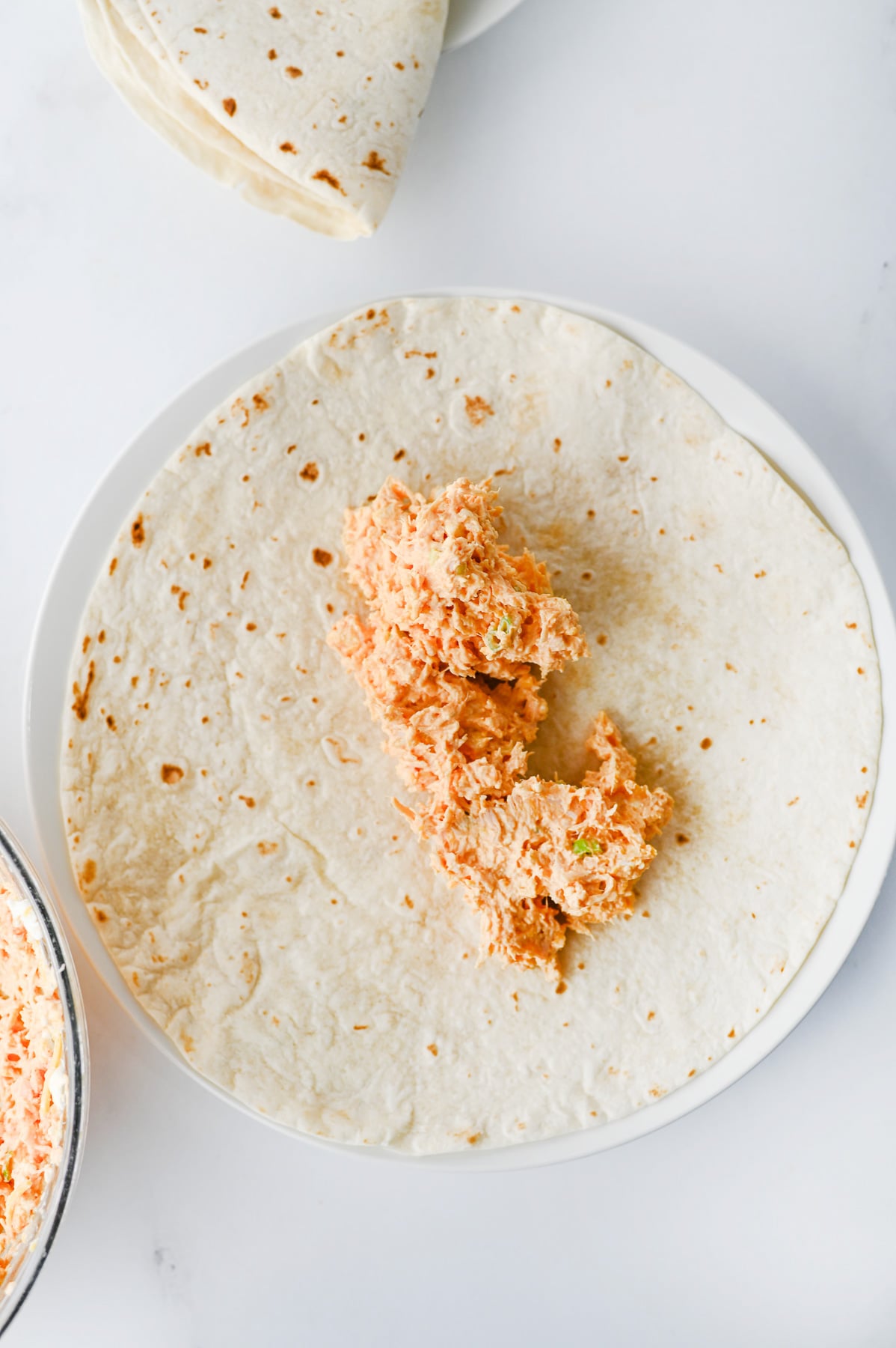 Chicken mixture is spread on tortilla.