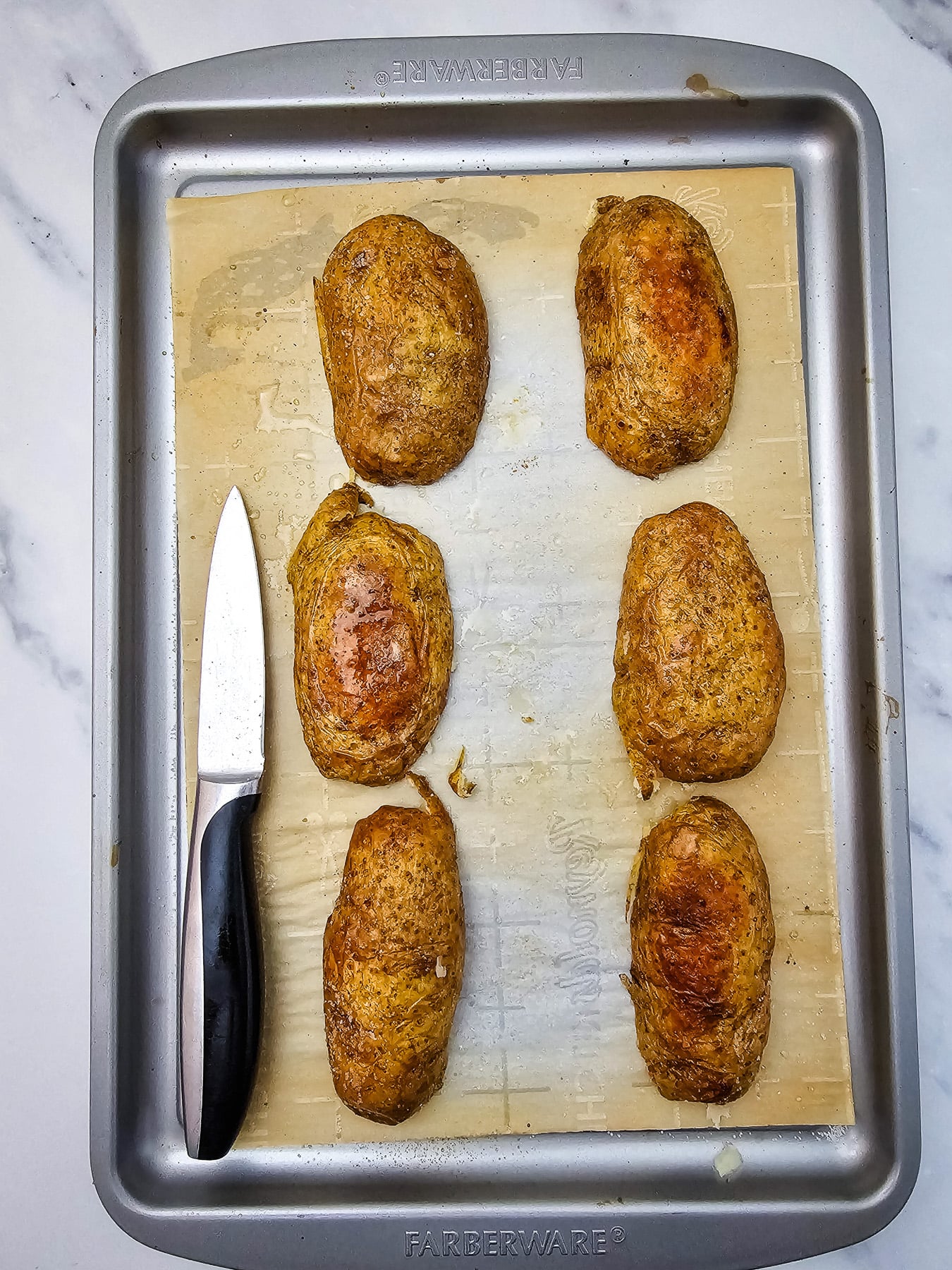 Sliced baked potatoes turned upside down on baking sheet.