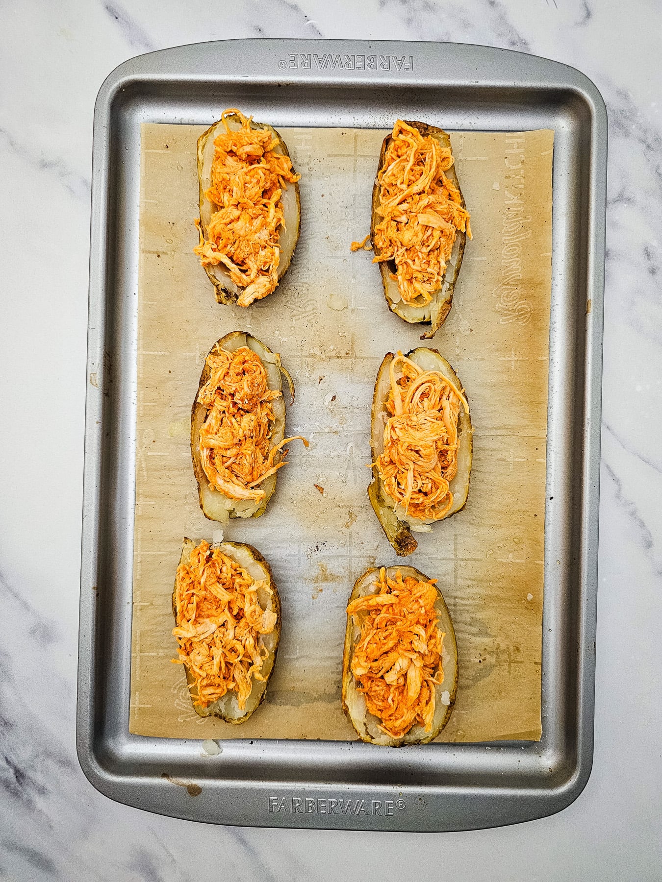 Stuffed baked potatoes on baking sheet ready to go into the oven.
