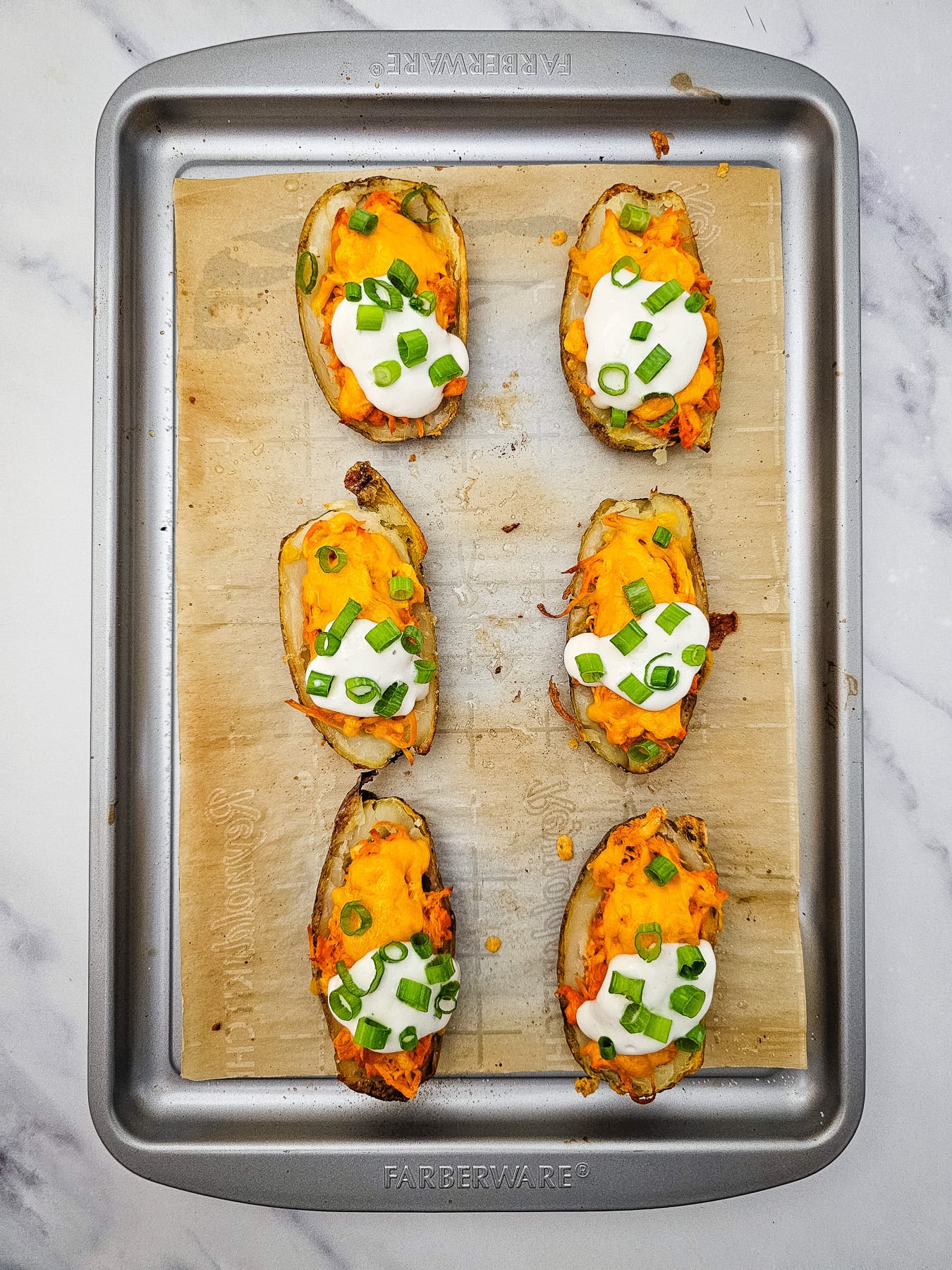 Blue cheese crumbles and onions on top of potato skins.