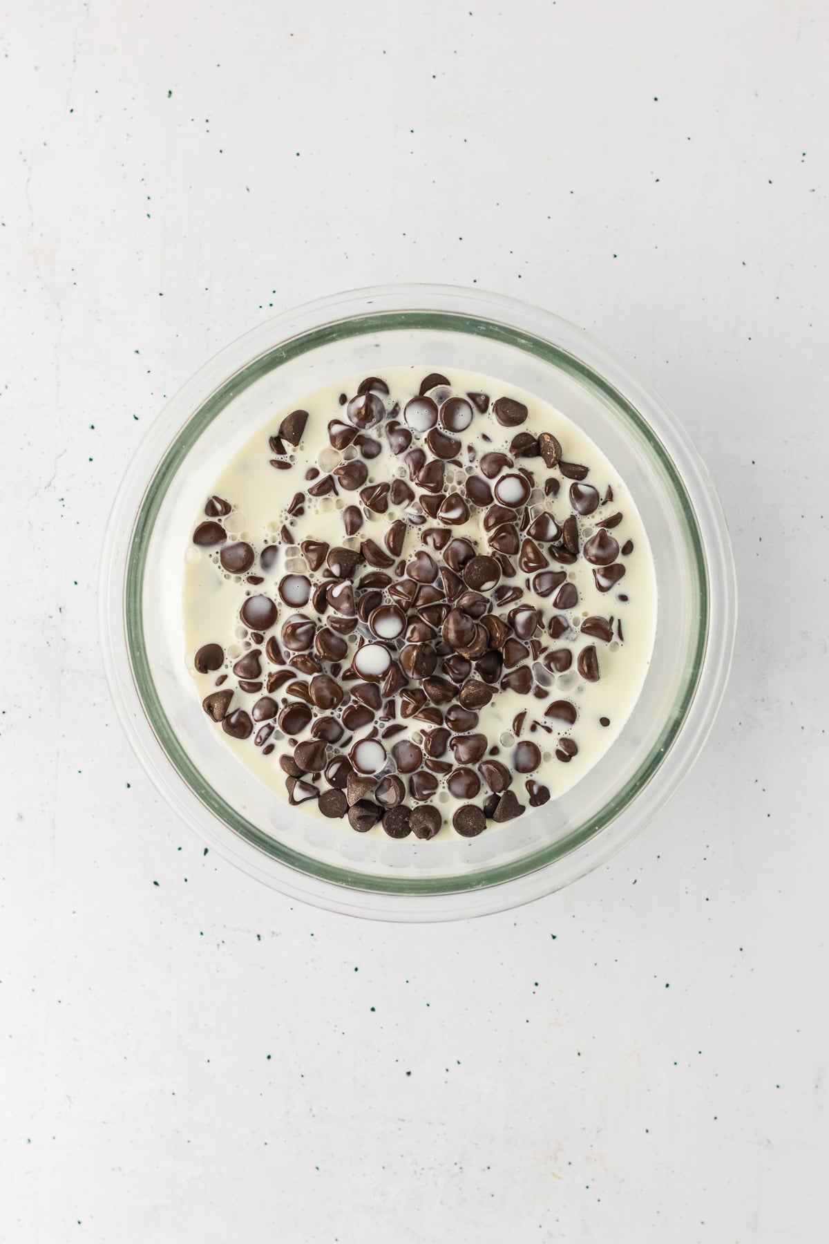 Chocolate chips and cream in small glass bowl.