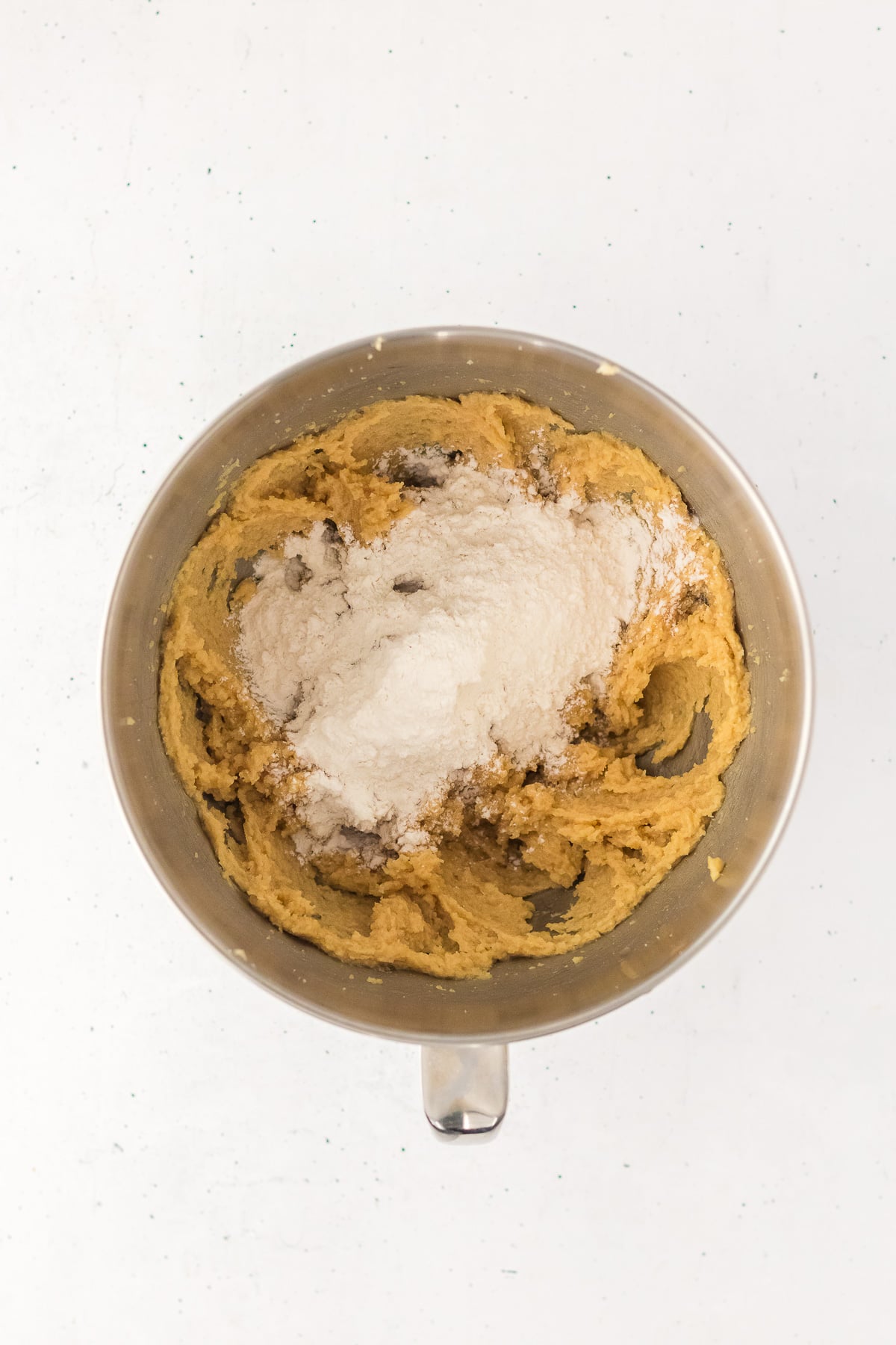 Flour mixture is added to the butter and sugar mixture in bowl form stand mixer.