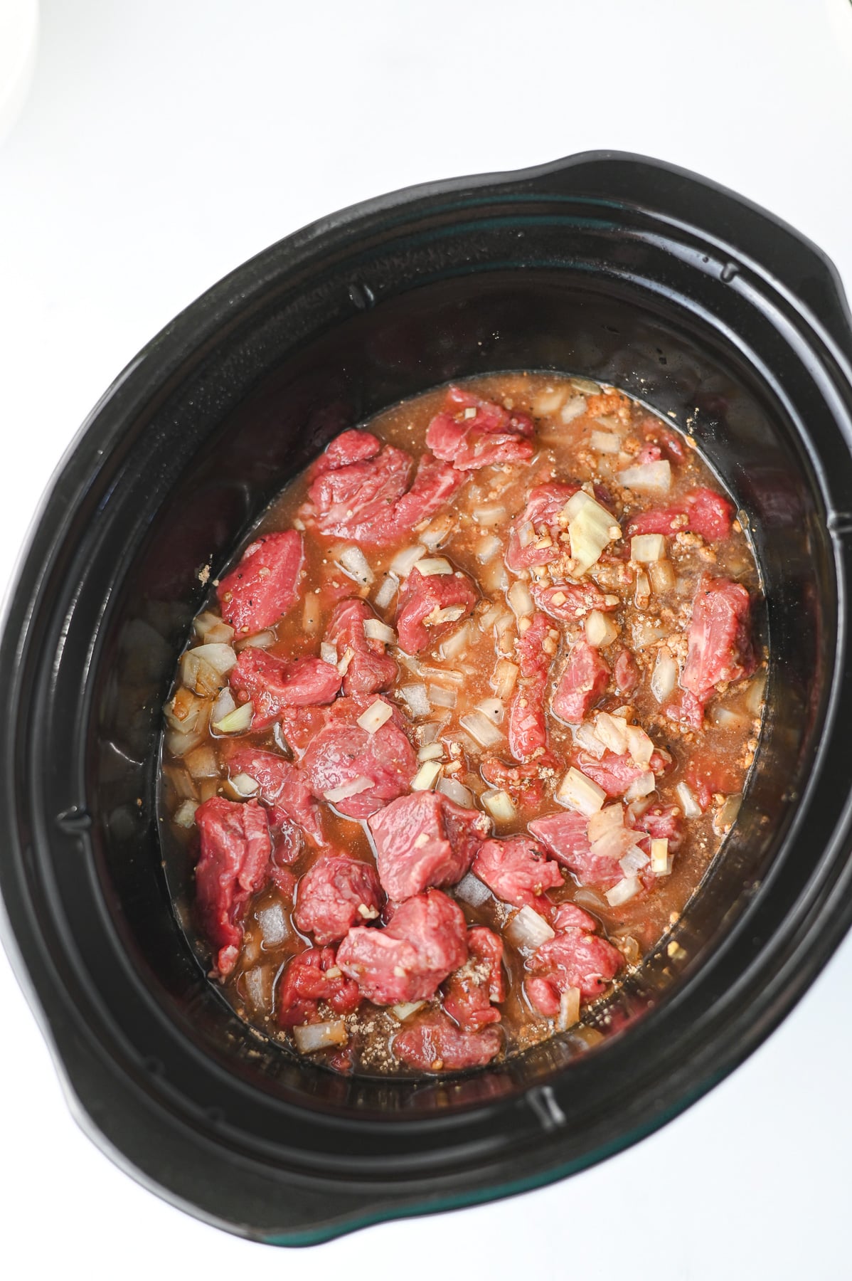 Water and beef broth is added to the beef mixture in the crockpot.