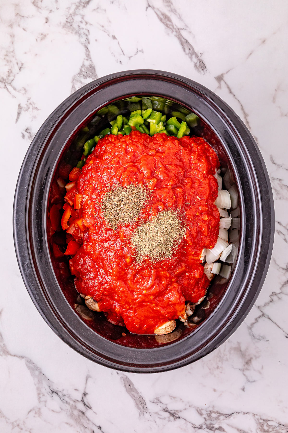 Tomato sauce and seasoning are added to the crockpot.