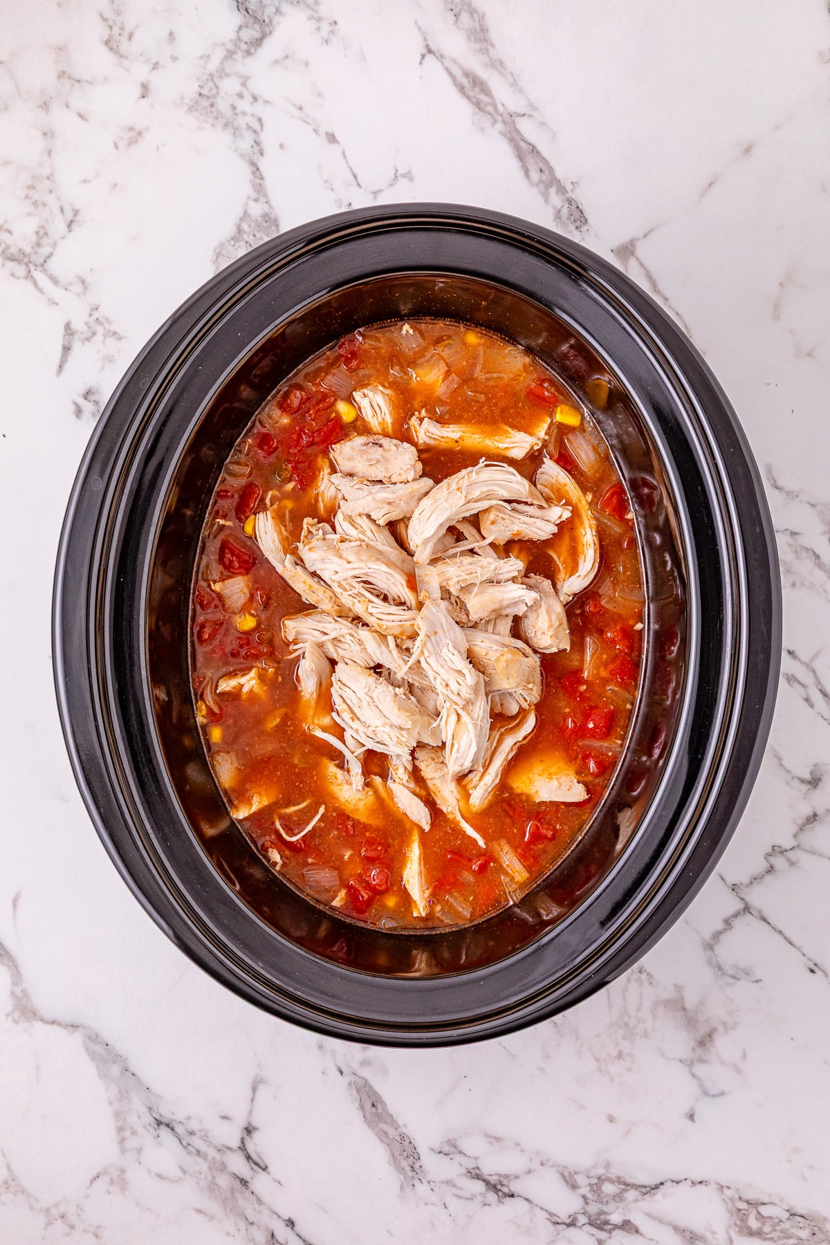 Shredded chicken is added back to the slow cooker.