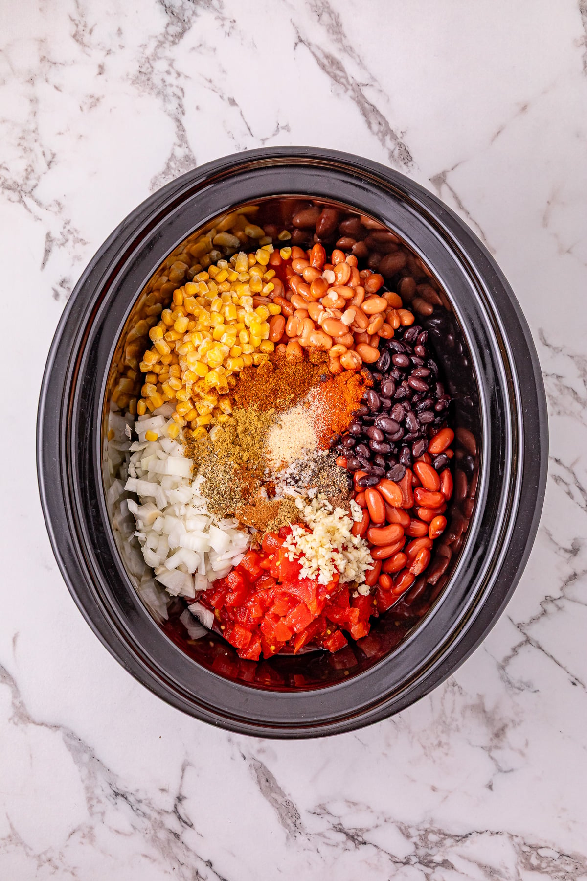 Remaining ingredients for chili are added to the top of the ground turkey in crockpot.