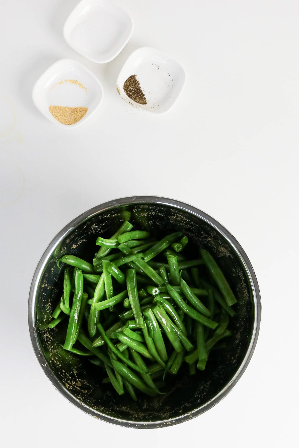 Green beans with seasoning in bowl.