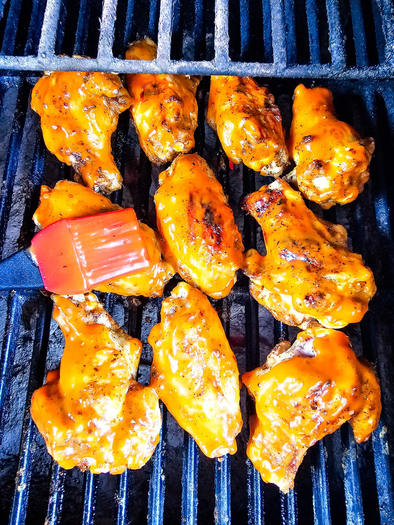 Wings are brushed with sauce on the grill.