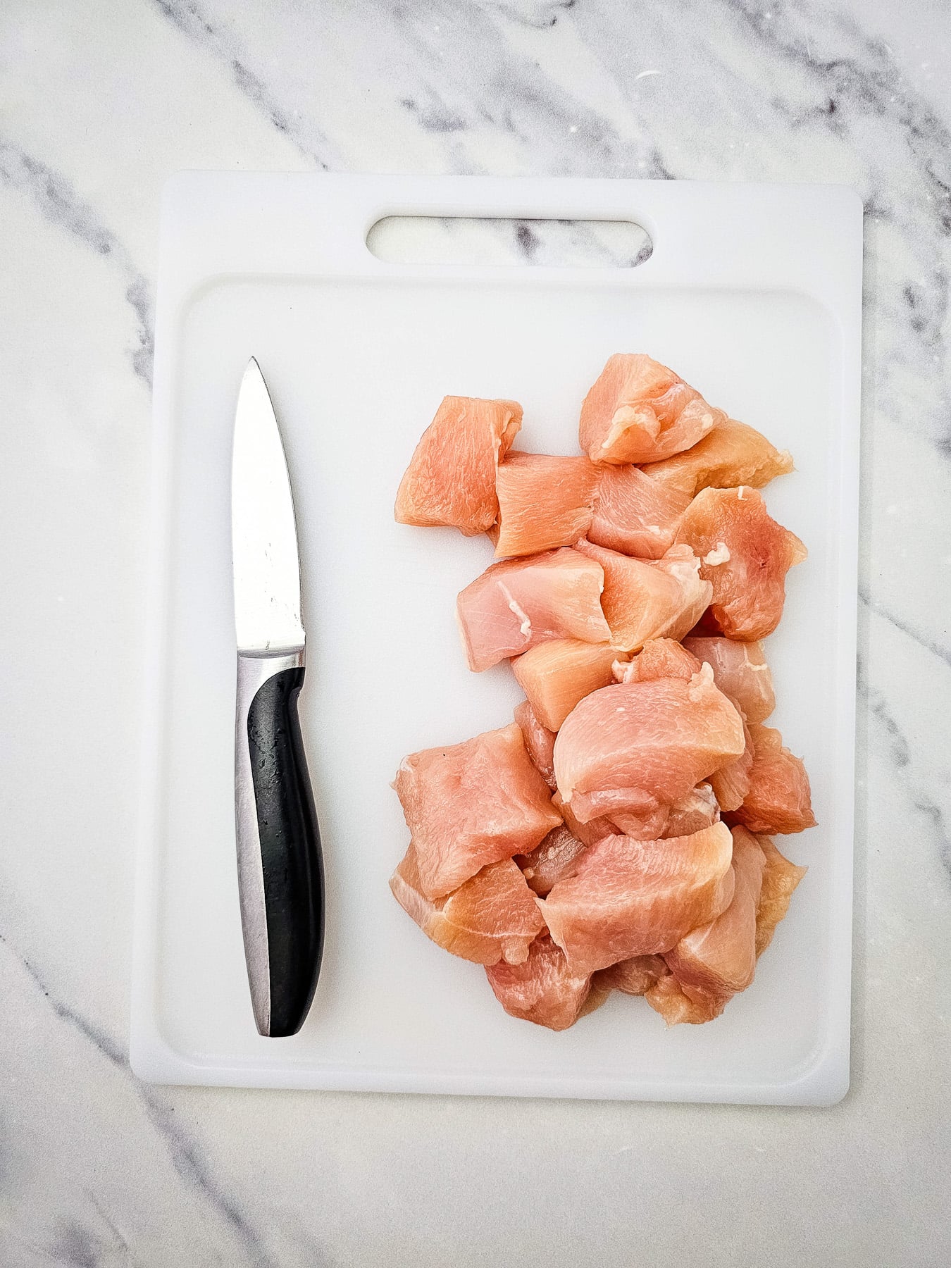 Cubed chicken on a cutting board.
