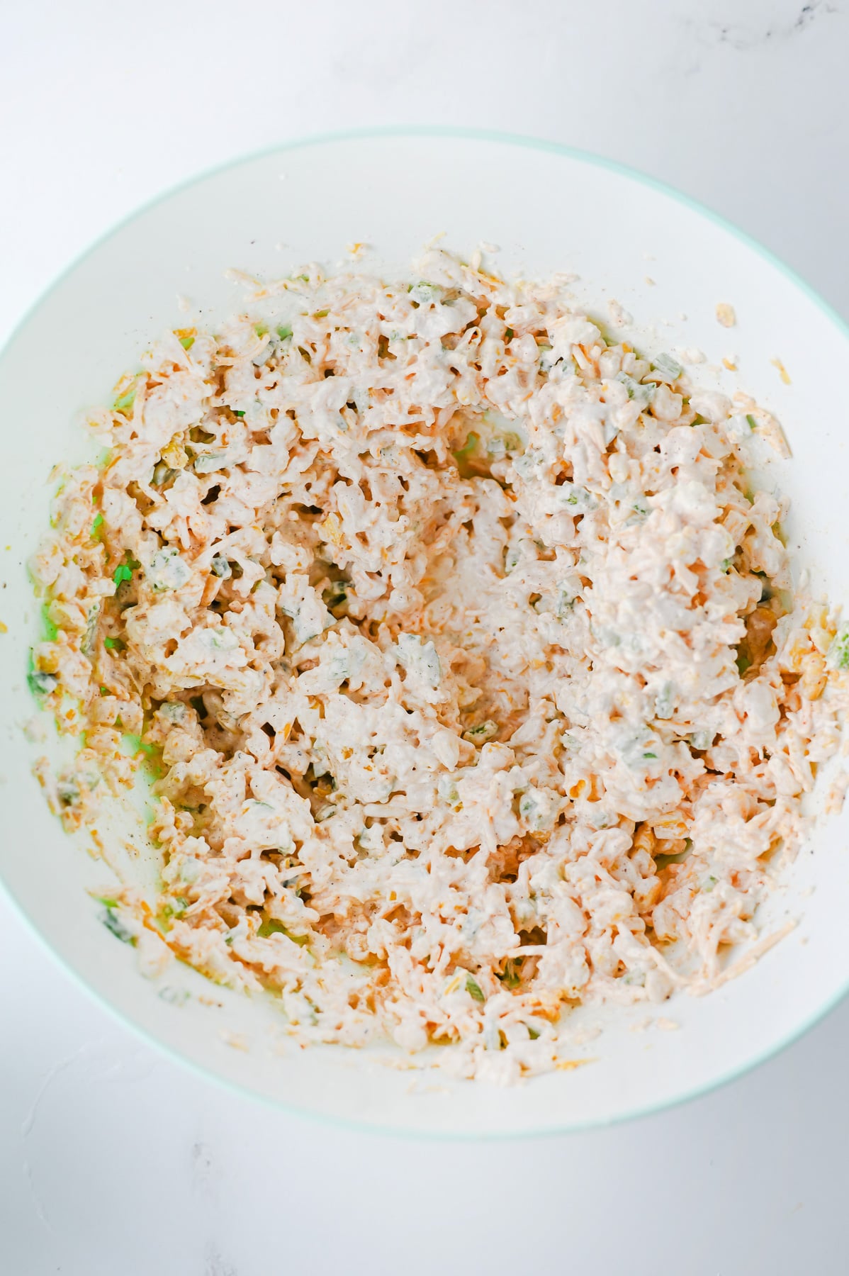 Corn, shredded cheddar cheese, diced jalapeño, chili powder, garlic powder, smoked paprika, salt, and black pepper is added to the cream cheese mixture in bowl.