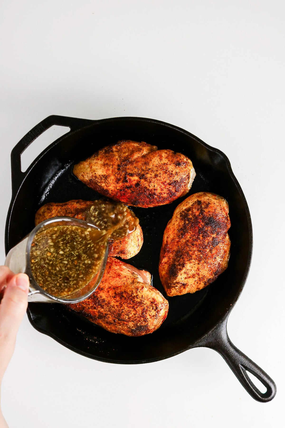 Mixture is poured over chicken in skillet.