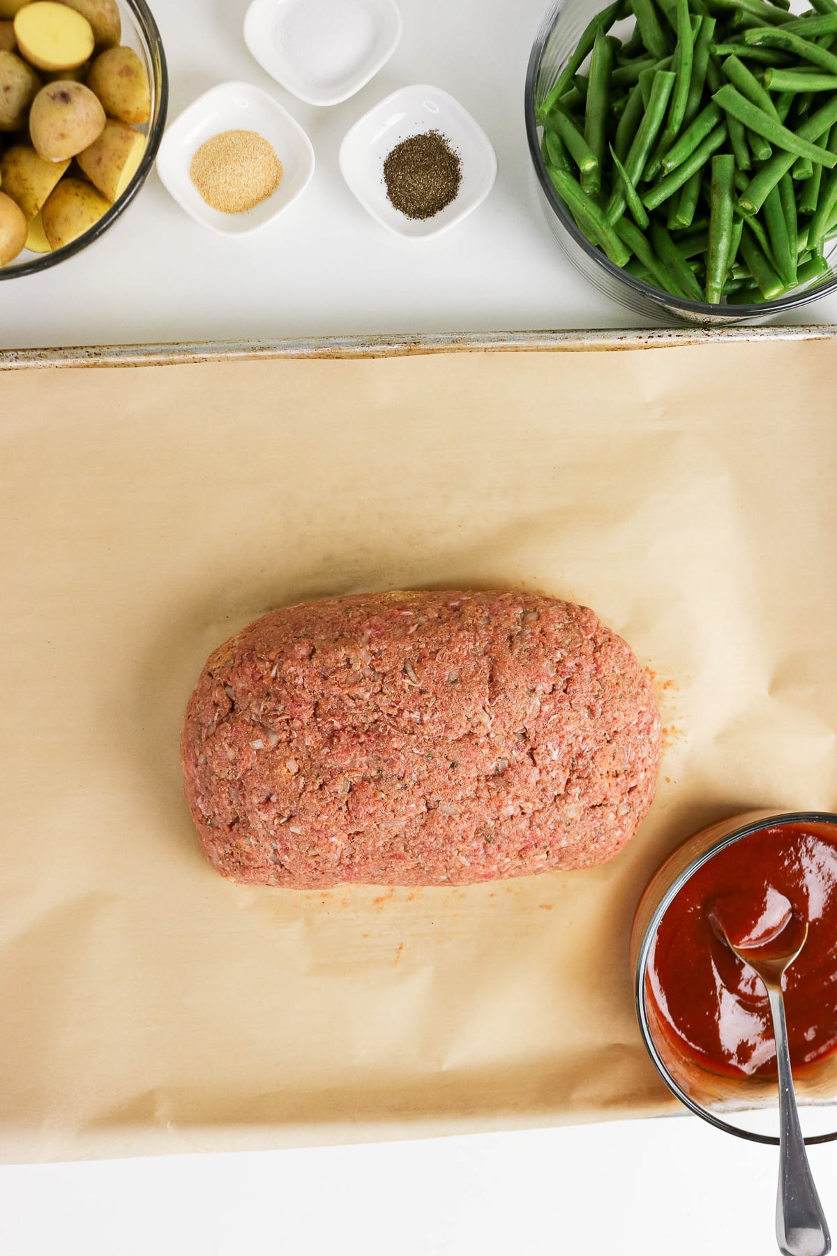 Shaped meatloaf on parchment-lined baking sheet.