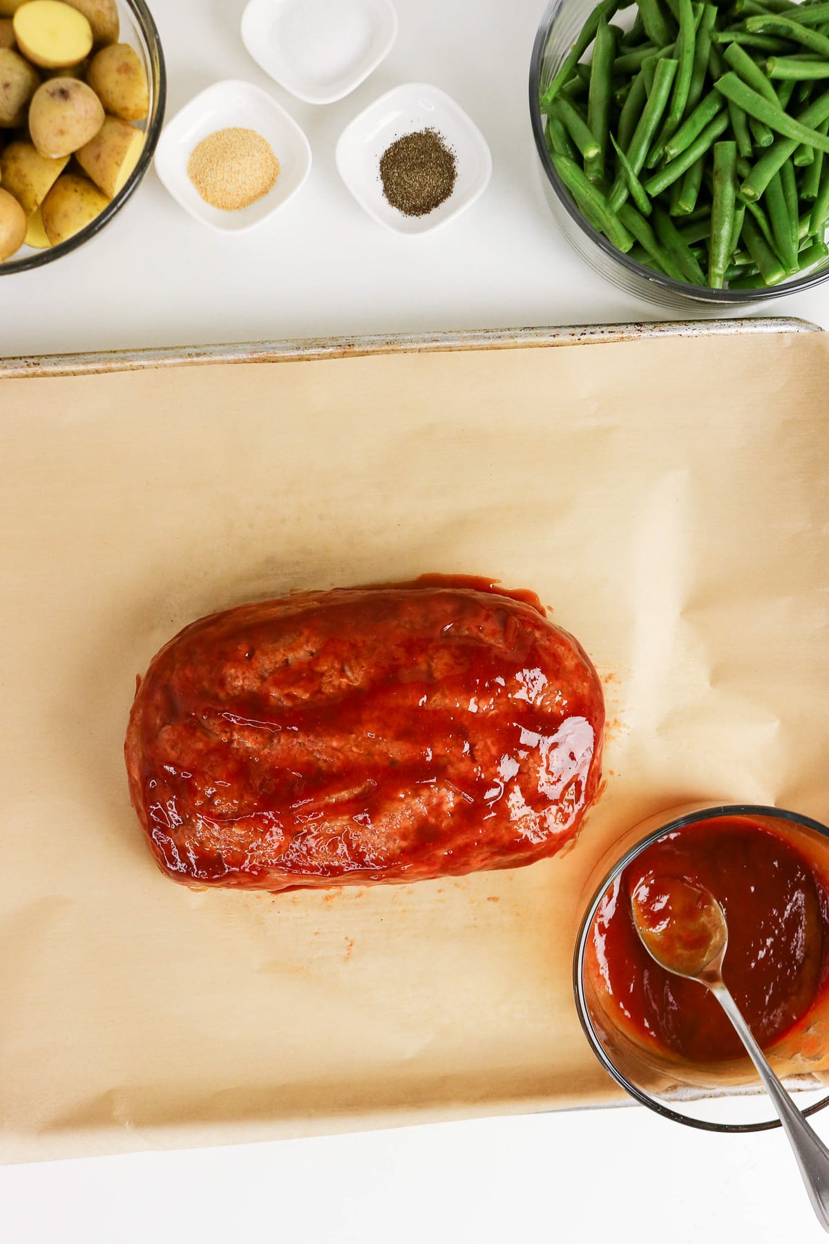 Glaze is spread on top of unbaked meatloaf.