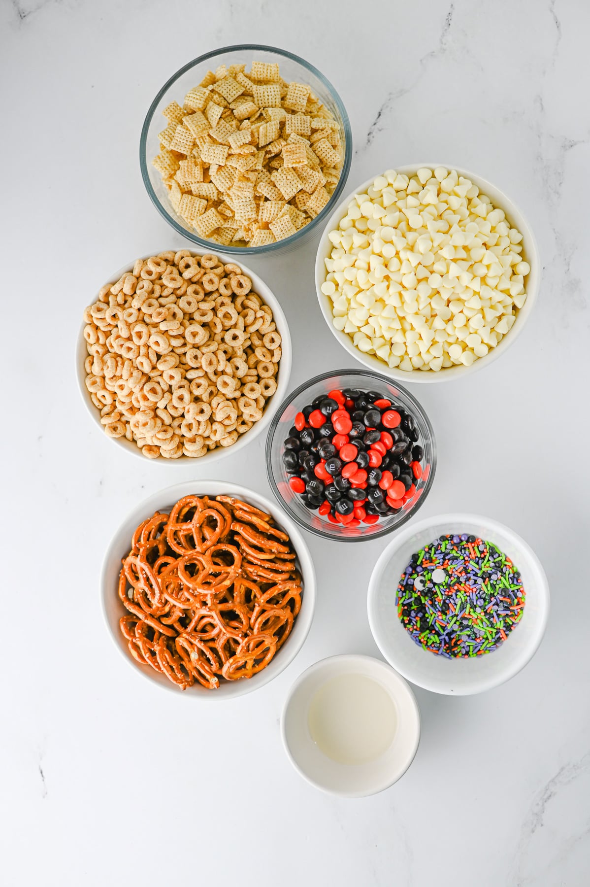Ingredients for monster munch halloween snack in small bowls on counter.