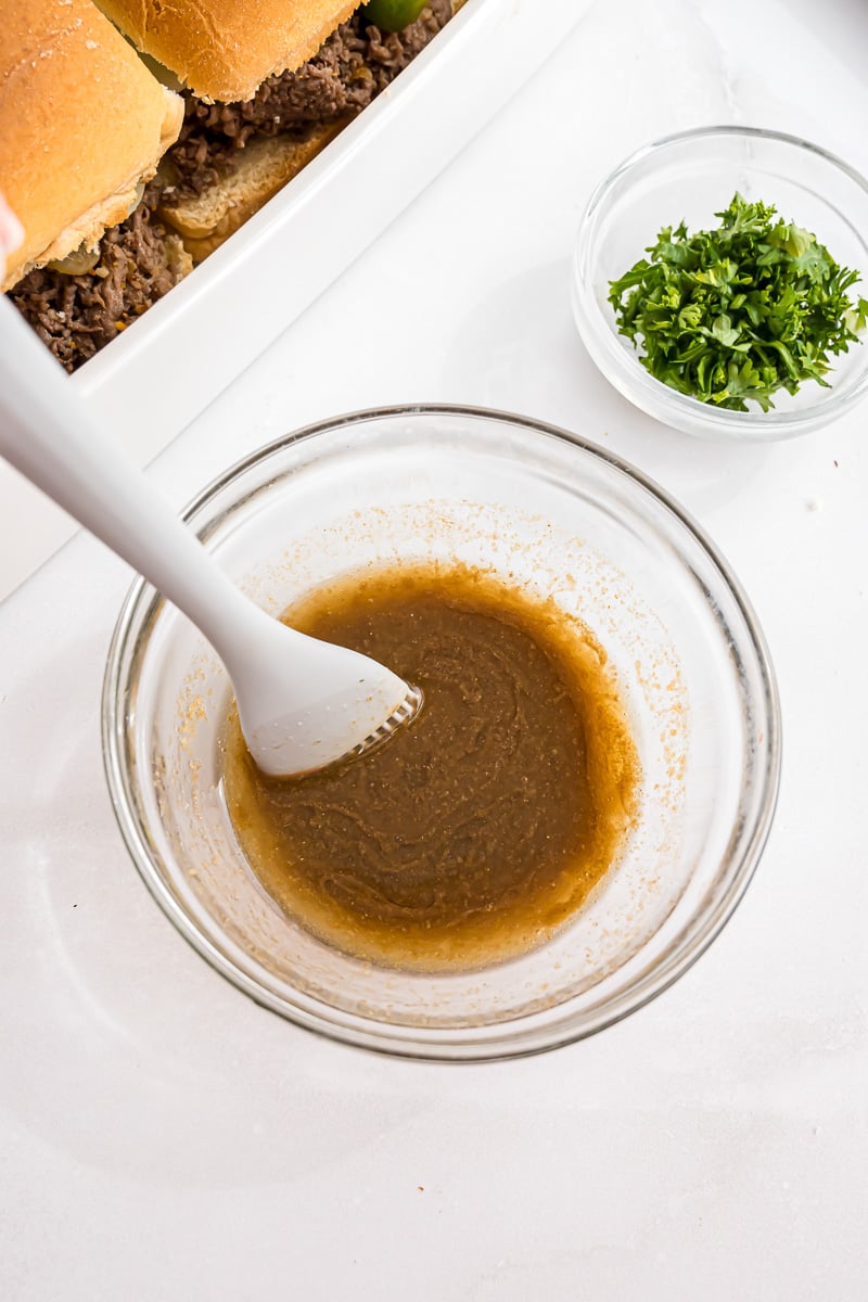 Melted butter, Worcestershire sauce, and garlic powder is mixed in a small bowl, ready to be brushed on top of sliders.