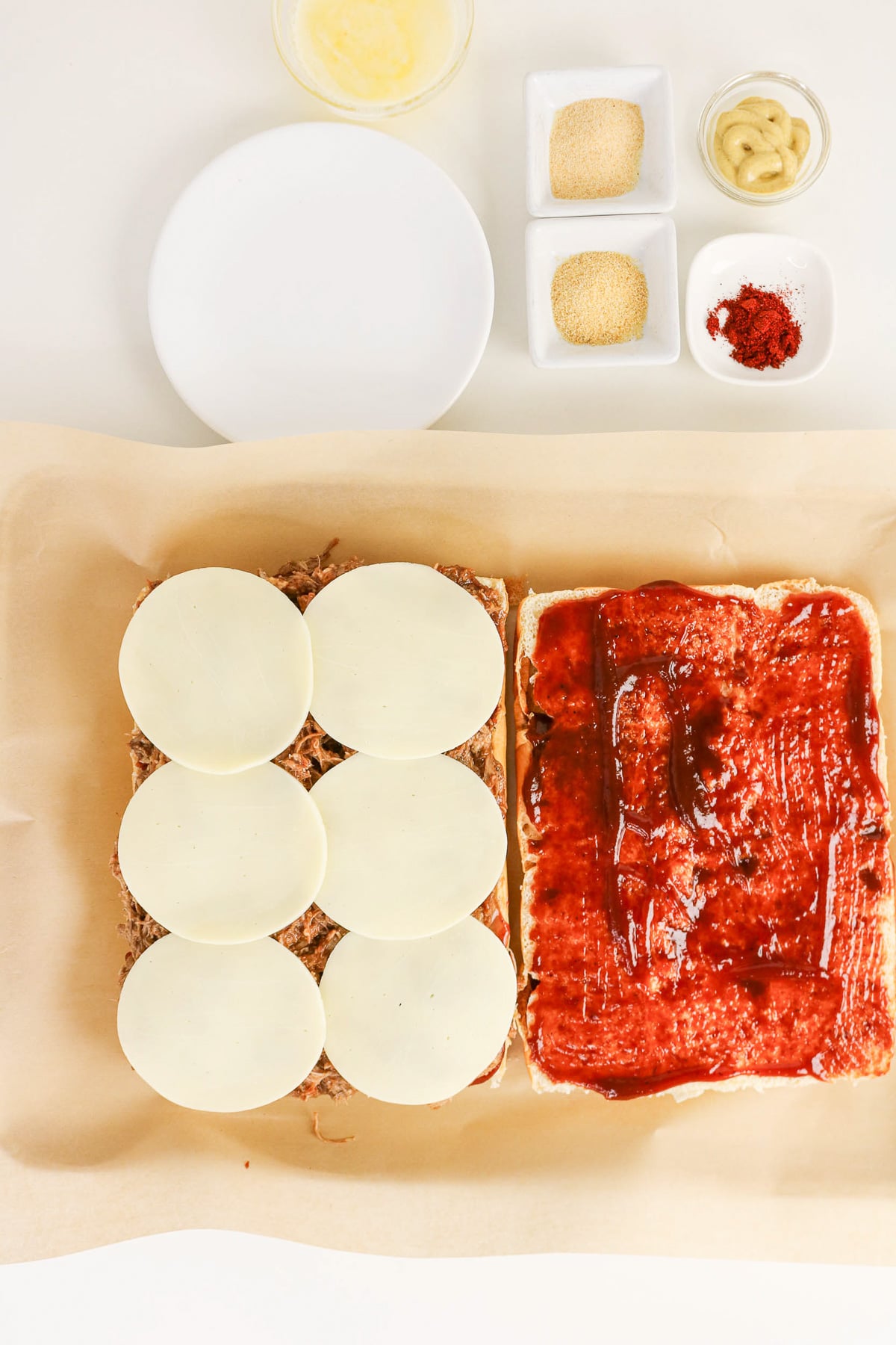 Provolone cheese is spread on bottom buns.