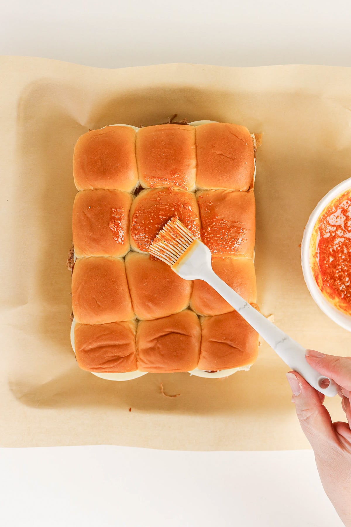 Topping mixture is spread on top of sliders.