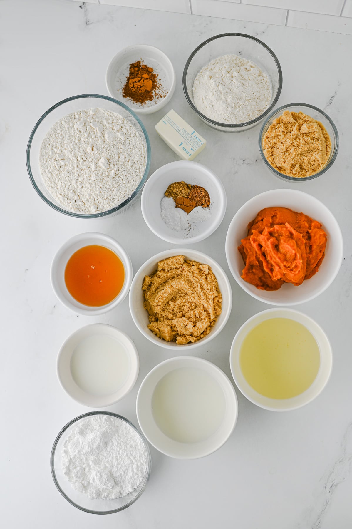 Pumpkin coffee cake ingredients laid out in small bowls on kitchen counter.