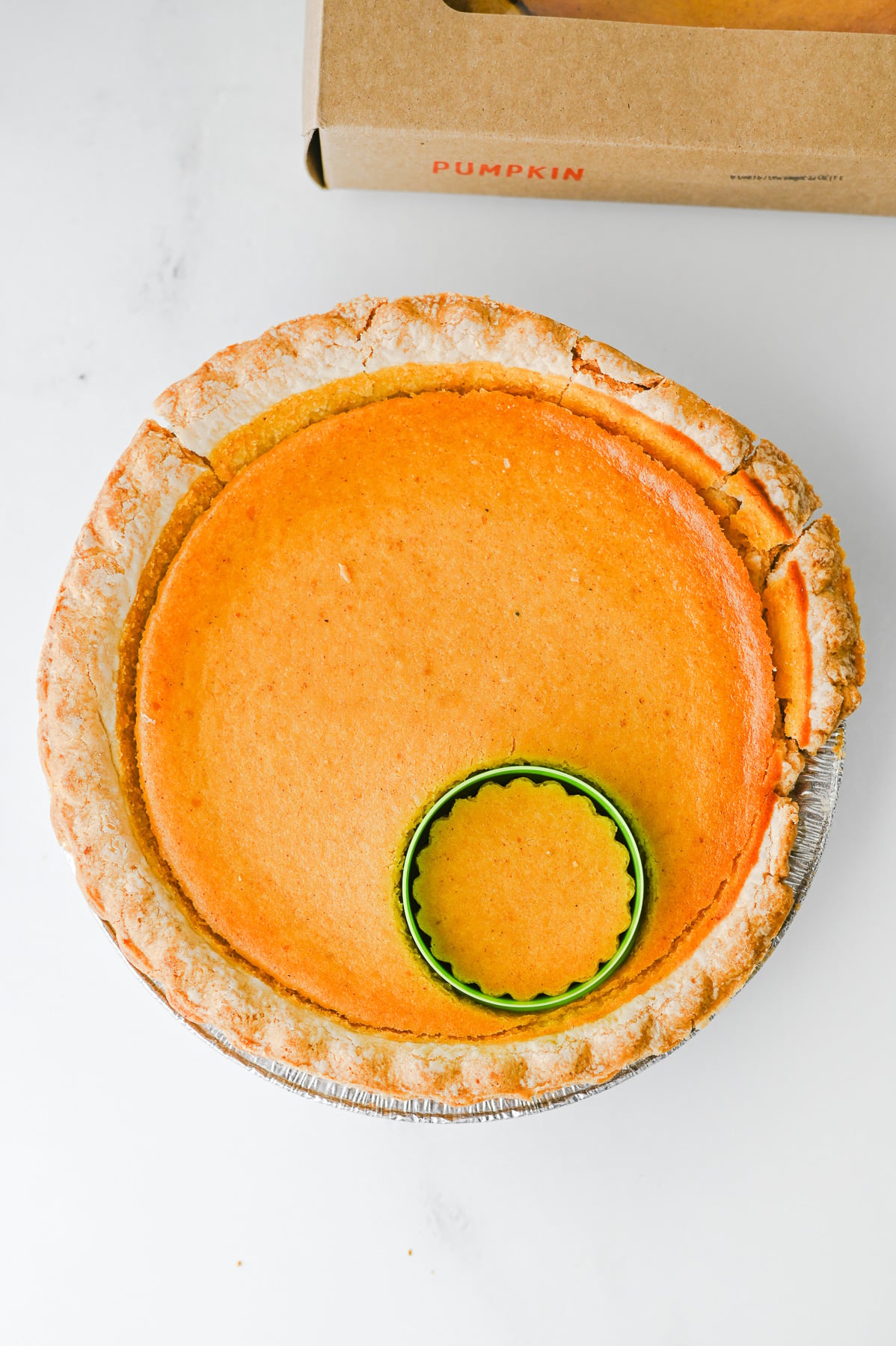 Cookie cutter is pressed into pumpkin pie.