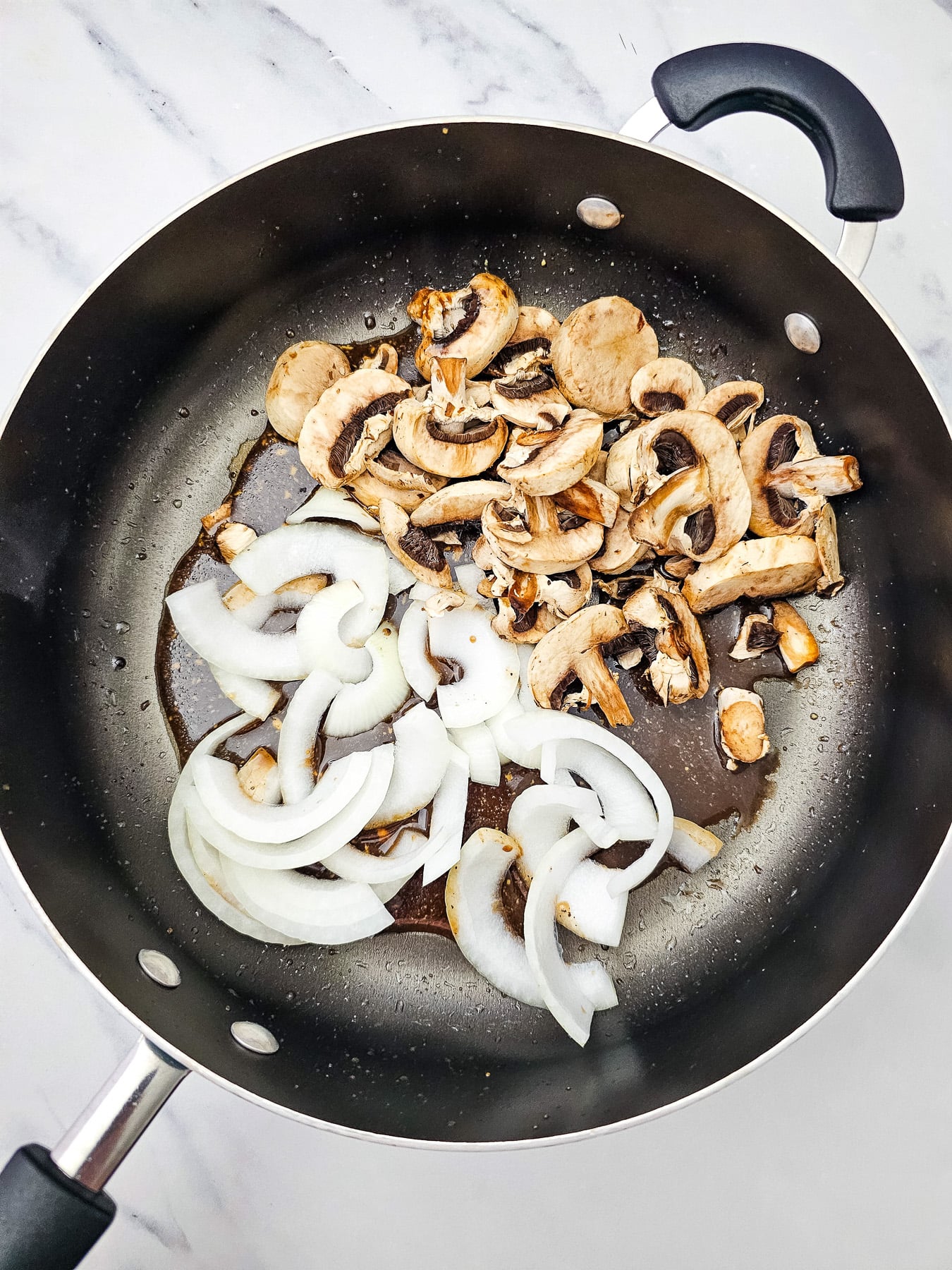 Onions and mushrooms are added to the skillet.