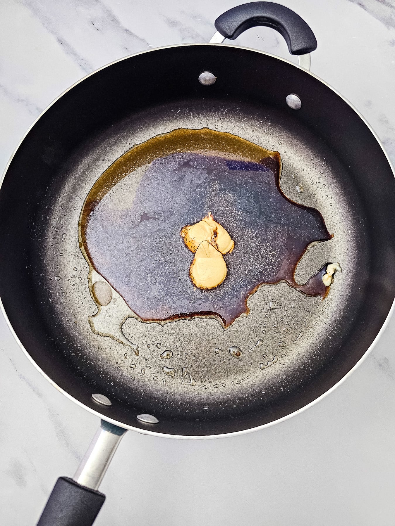 Maple syrup and dijon is whisked into skillet.