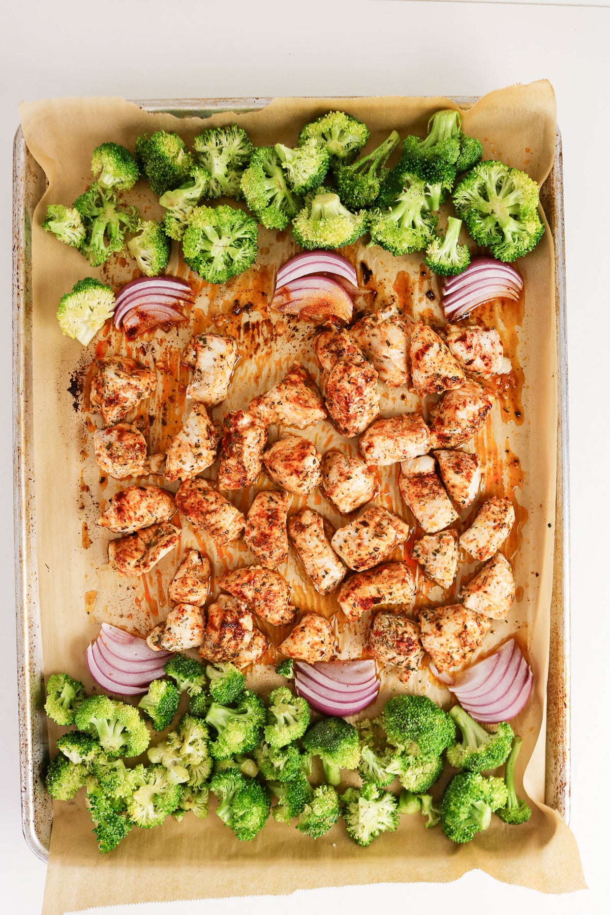 Broccoli is arranged on both ends of baking pan with the chicken.