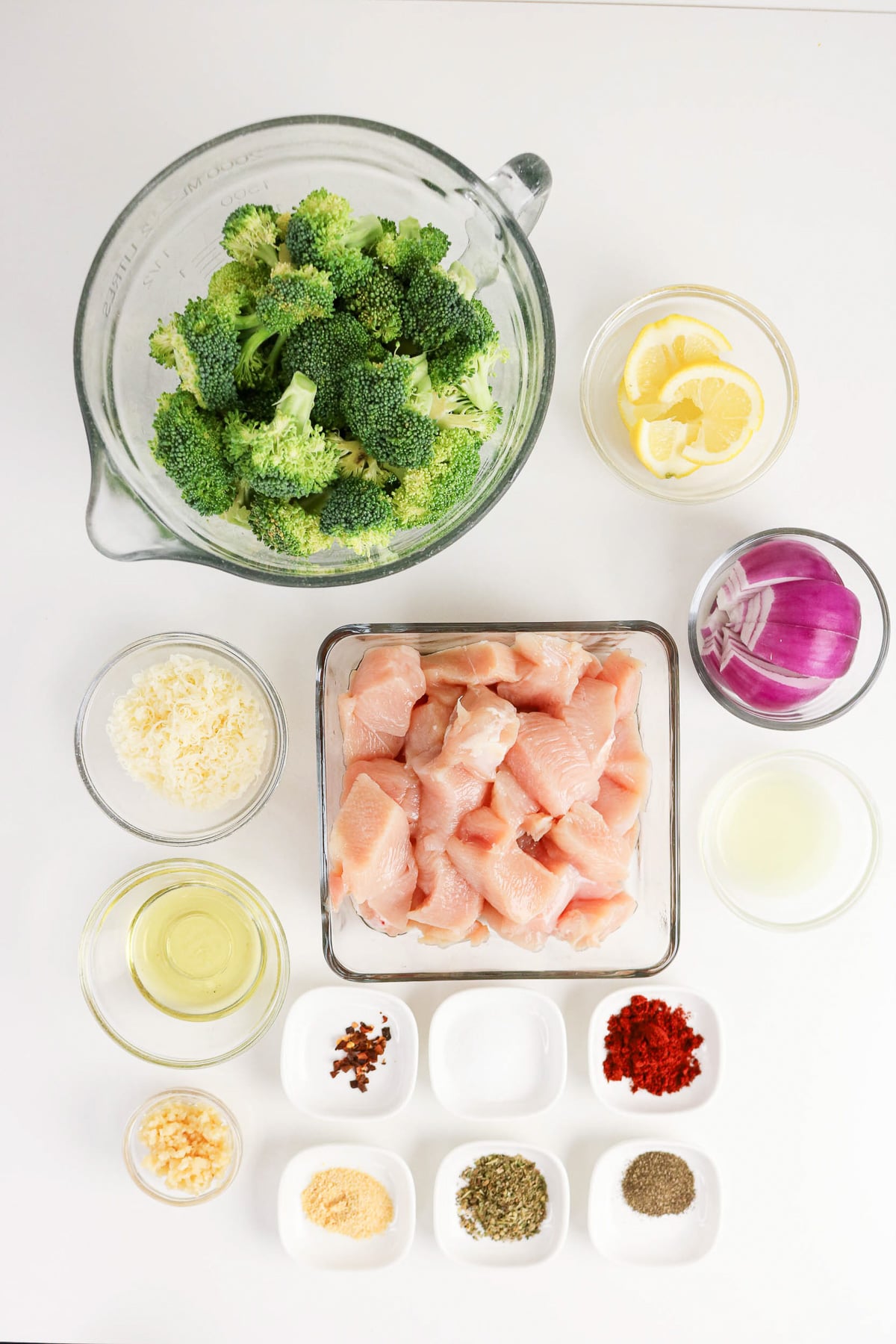 Ingredients for sheet pan chicken and broccoli in small bowls on counter in preparation for the recipe.