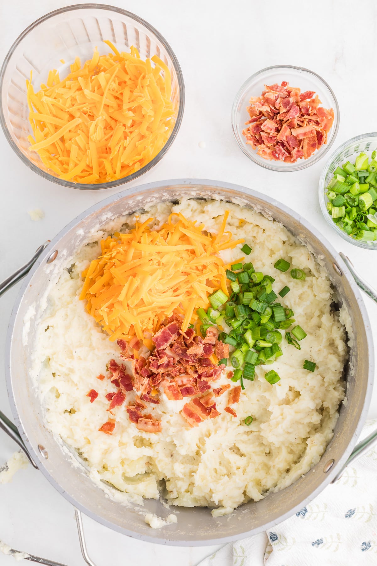 Cheese, half the bacon, and half the green onion slices are added to the mashed potatoes.