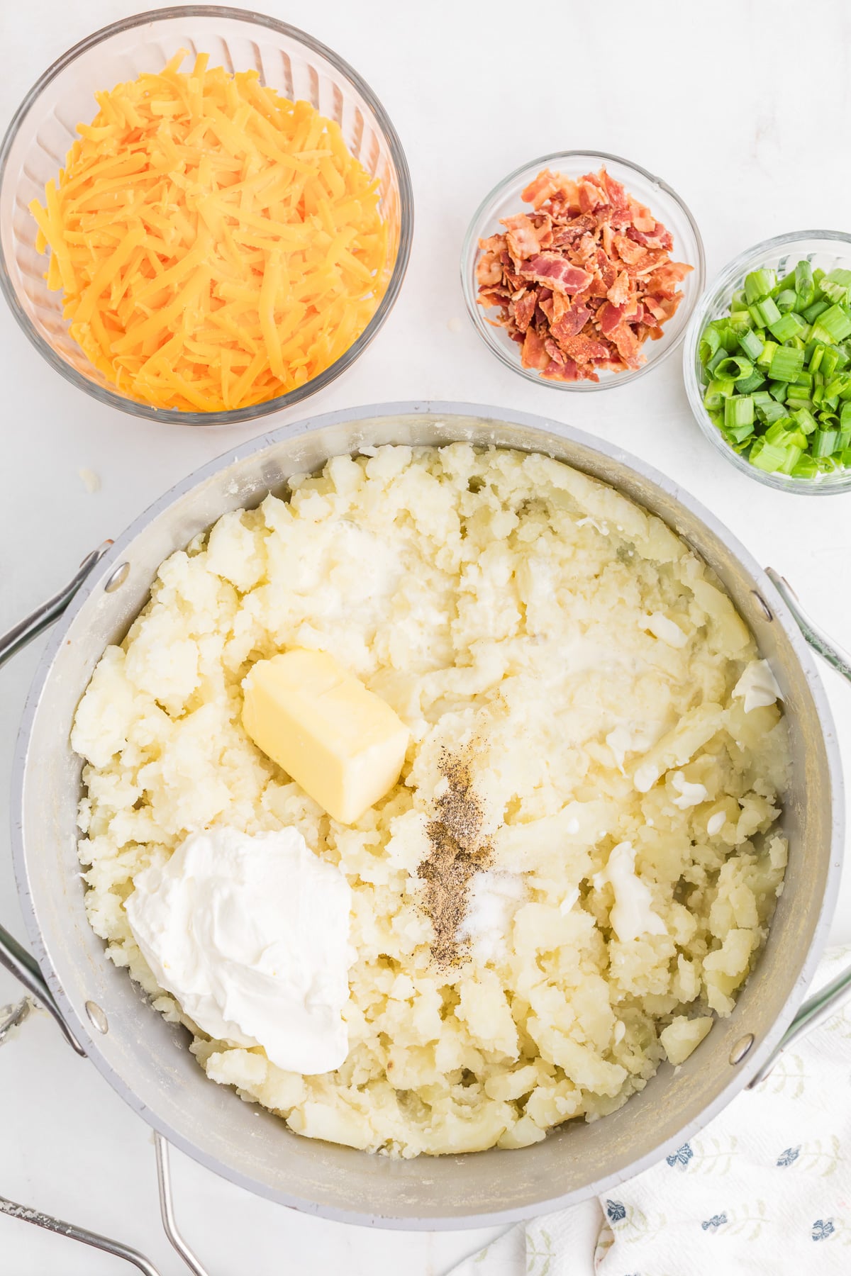Sour cream, heavy whipping cream, butter, salt, and pepper are added to the mashed potatoes.
