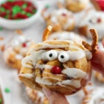 Reindeer cinnamon roll held up over baking dish.