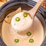 Crockpot queso blanco scooped up in a ladle held over crockpot.