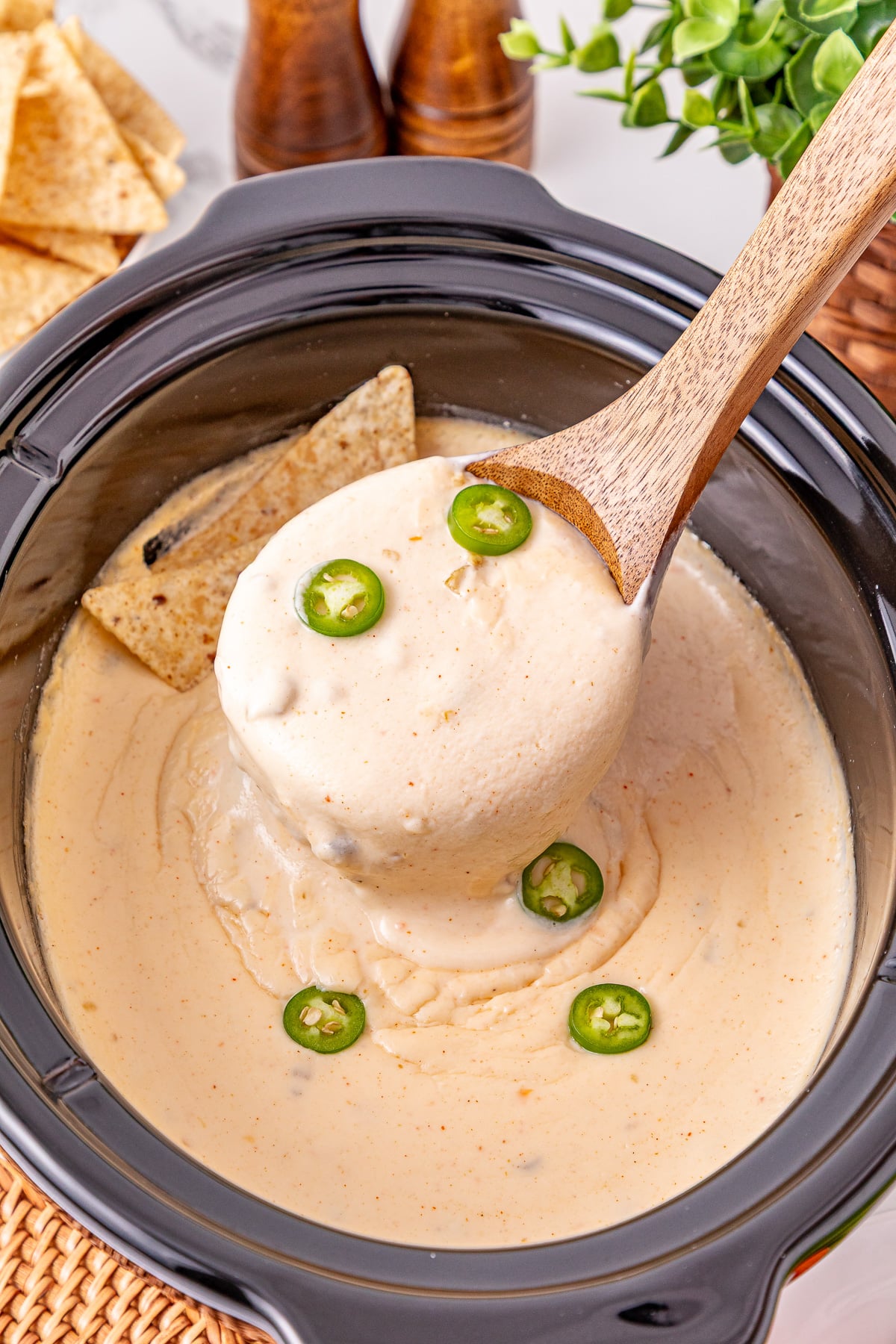 Crockpot queso blanco scooped up in a ladle held over crockpot.