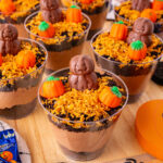 Pumpkin patch dirt cups single-serve desserts on a wooden tray for a fall party.