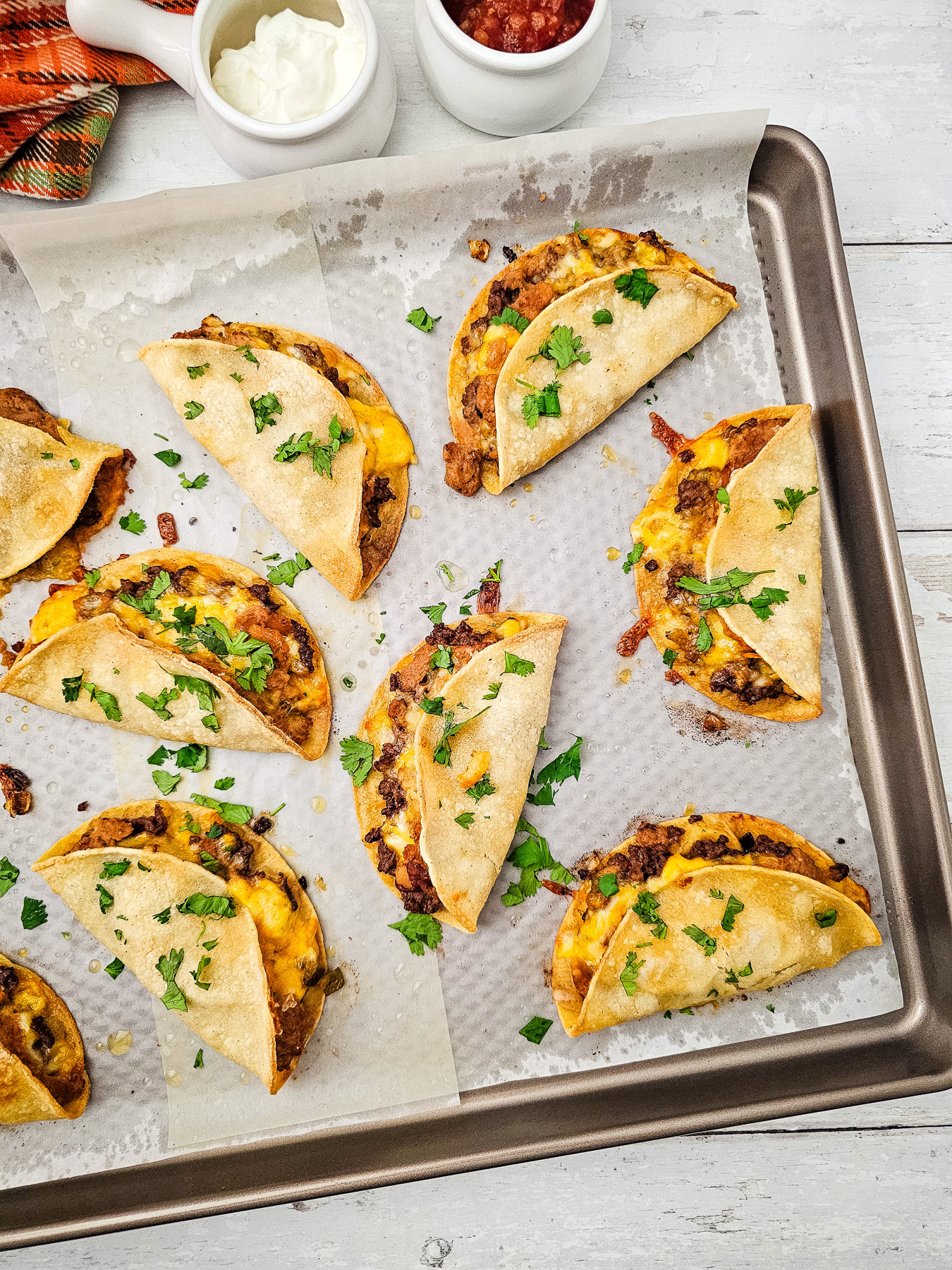 Crispy cheesy baked beef tacos on baking sheet, ready to be served.